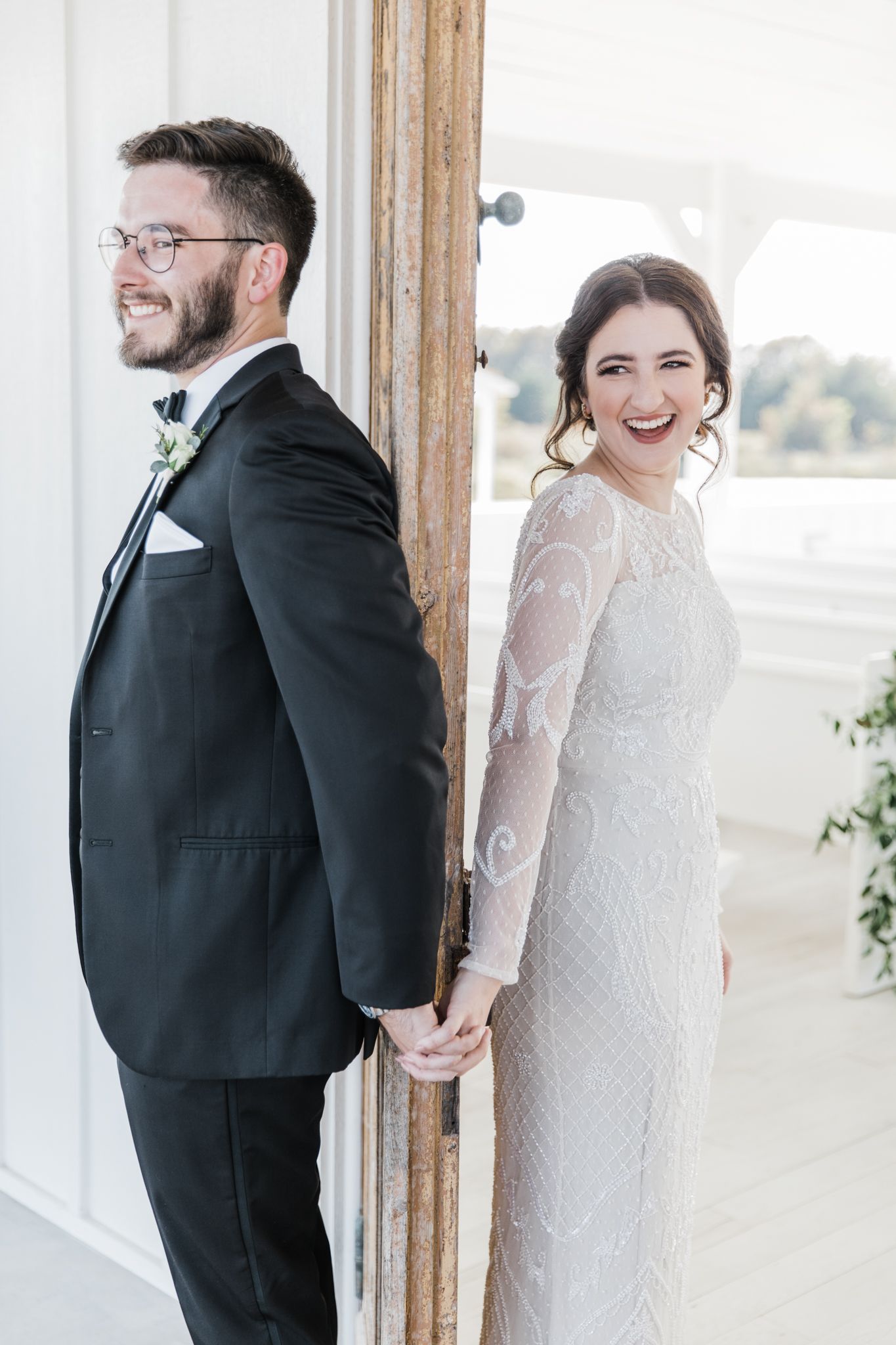 First touch for the bride and groom with their hands interlocked with a door in between them.