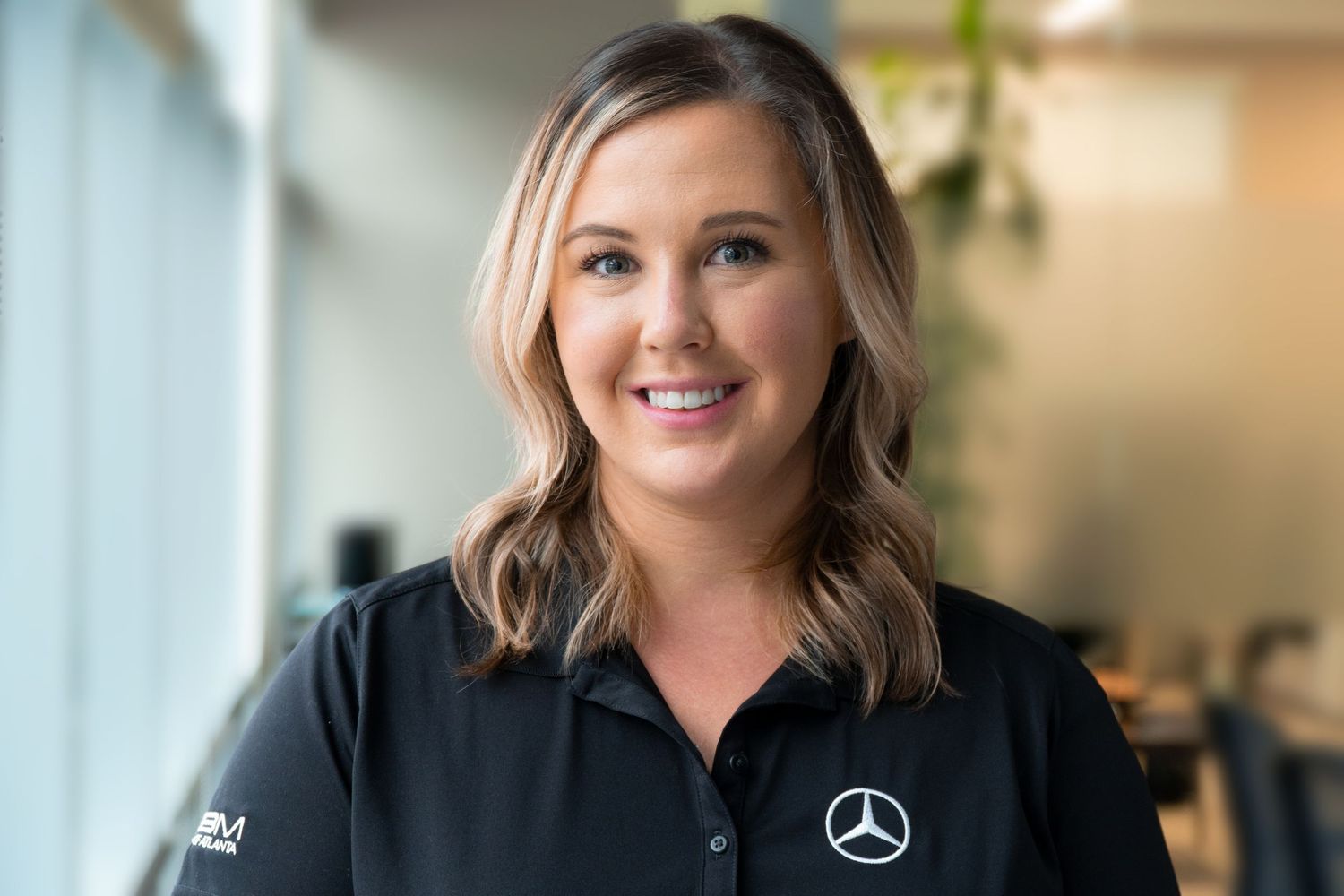 Professional wearing a Mercedes-Benz branded polo shirt in an office setting.