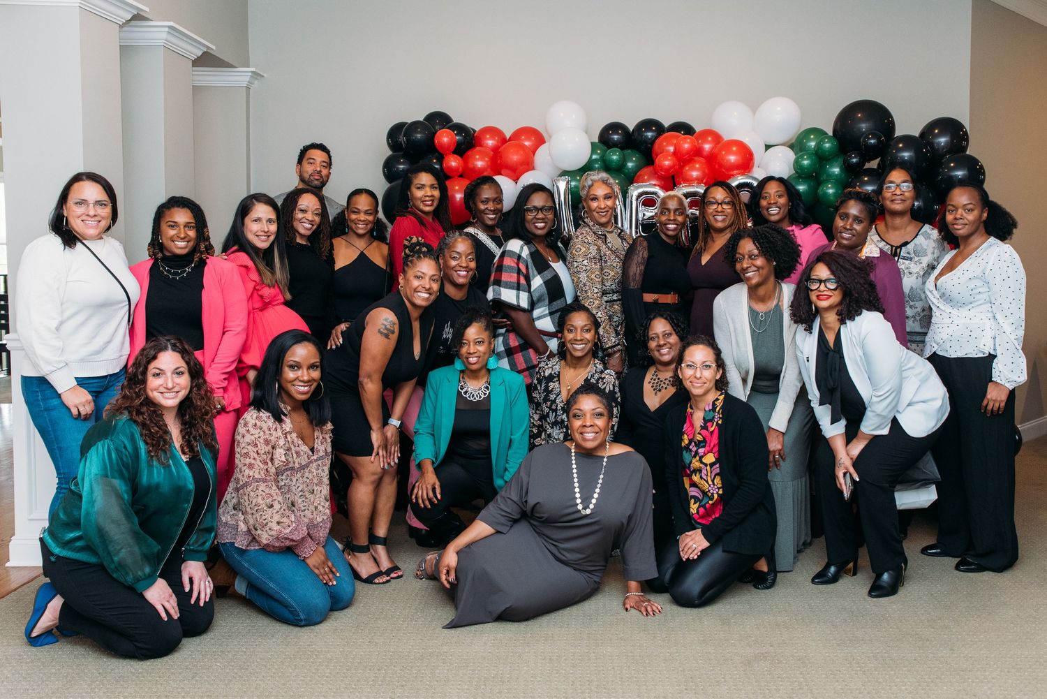 Large group photo of event attendees sitting together against a wall.
