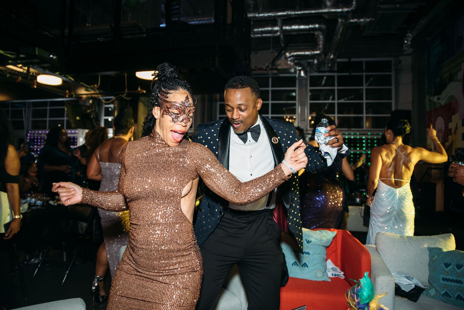 People dancing and celebrating at a dimly lit indoor event.