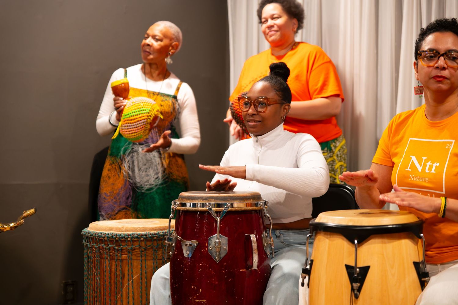 Group of musicians playing percussion instruments in bright orange and white outfits.