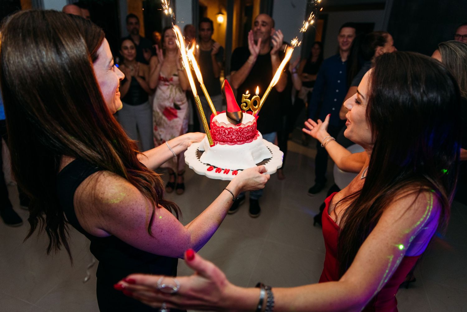 Sparklers illuminate a dark dance floor as party guests celebrate.