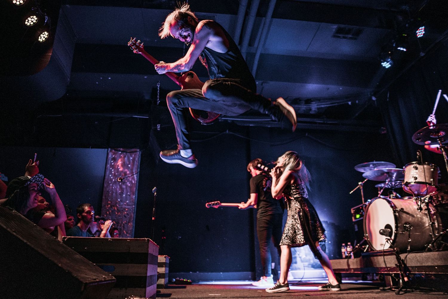 Rock concert performance with dramatic stage lighting and musicians in silhouette.