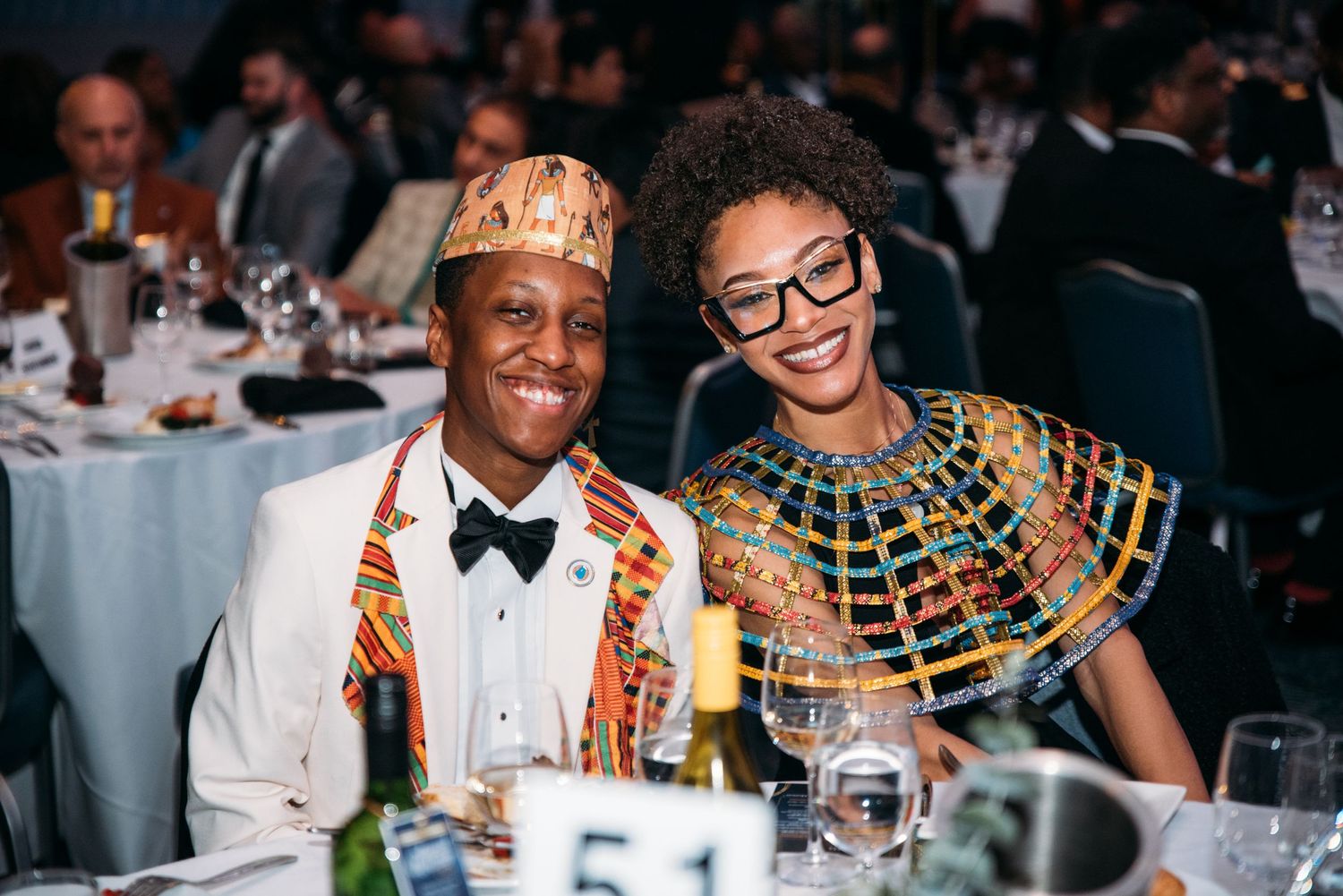 Formal dinner event with guests in traditional African attire at decorated tables.