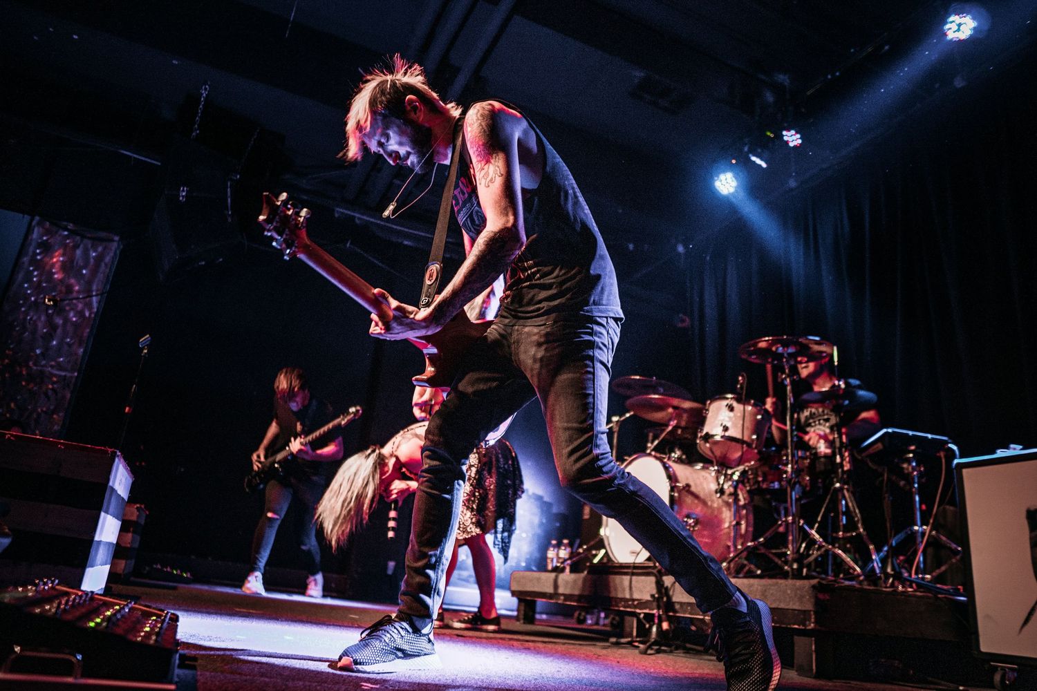 Live music performance on stage with dramatic lighting and performers in action.