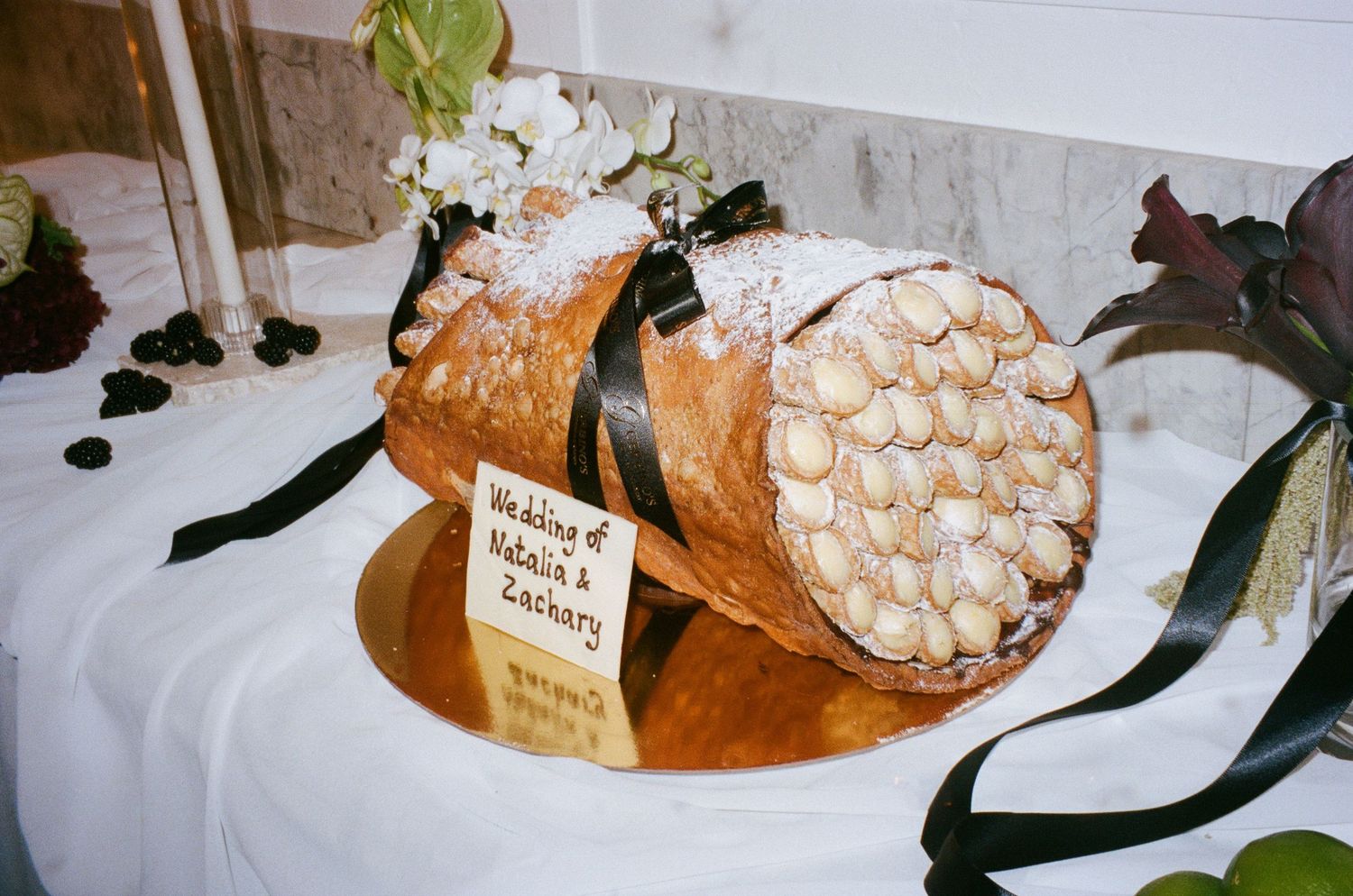 A series of cheese and appetizers stands displayed on white tabletops at a catered event.