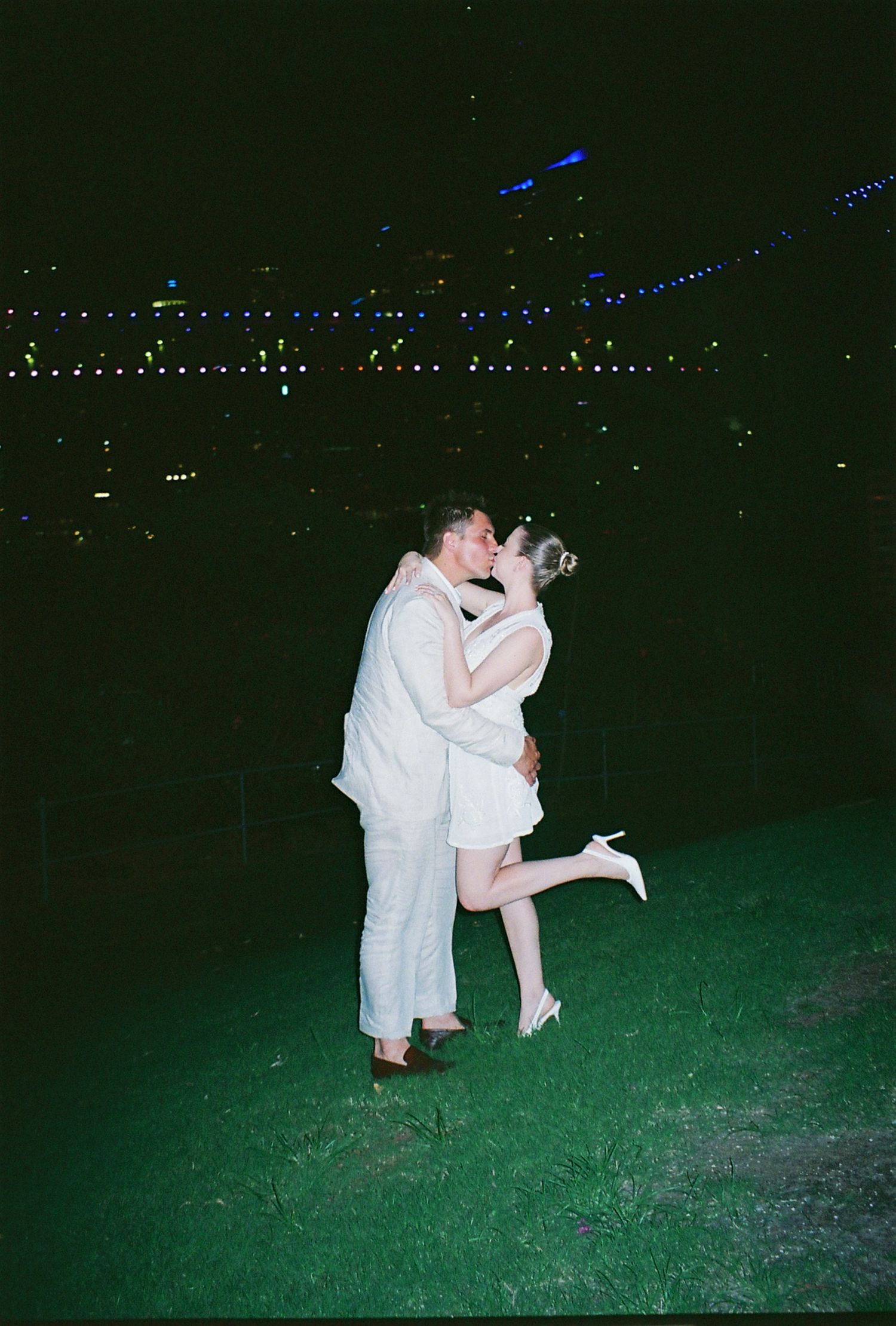 A romantic nighttime embrace with city lights twinkling in the background.