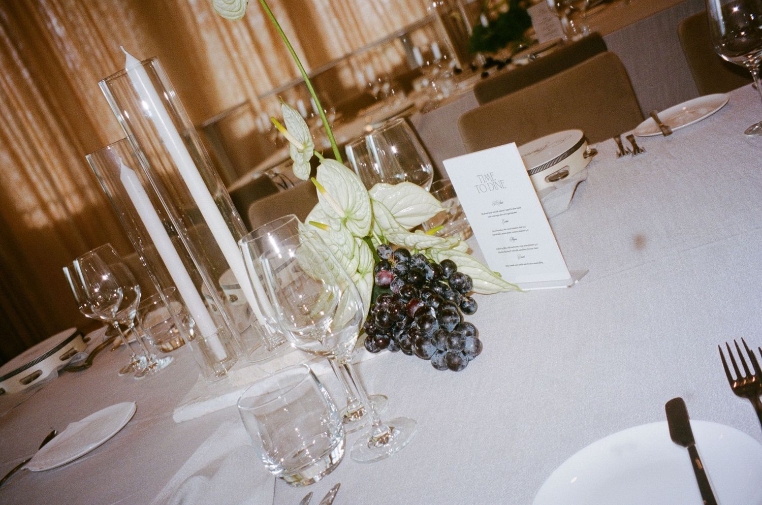 Table settings at an upscale wedding reception with glassware and place settings in soft focus.