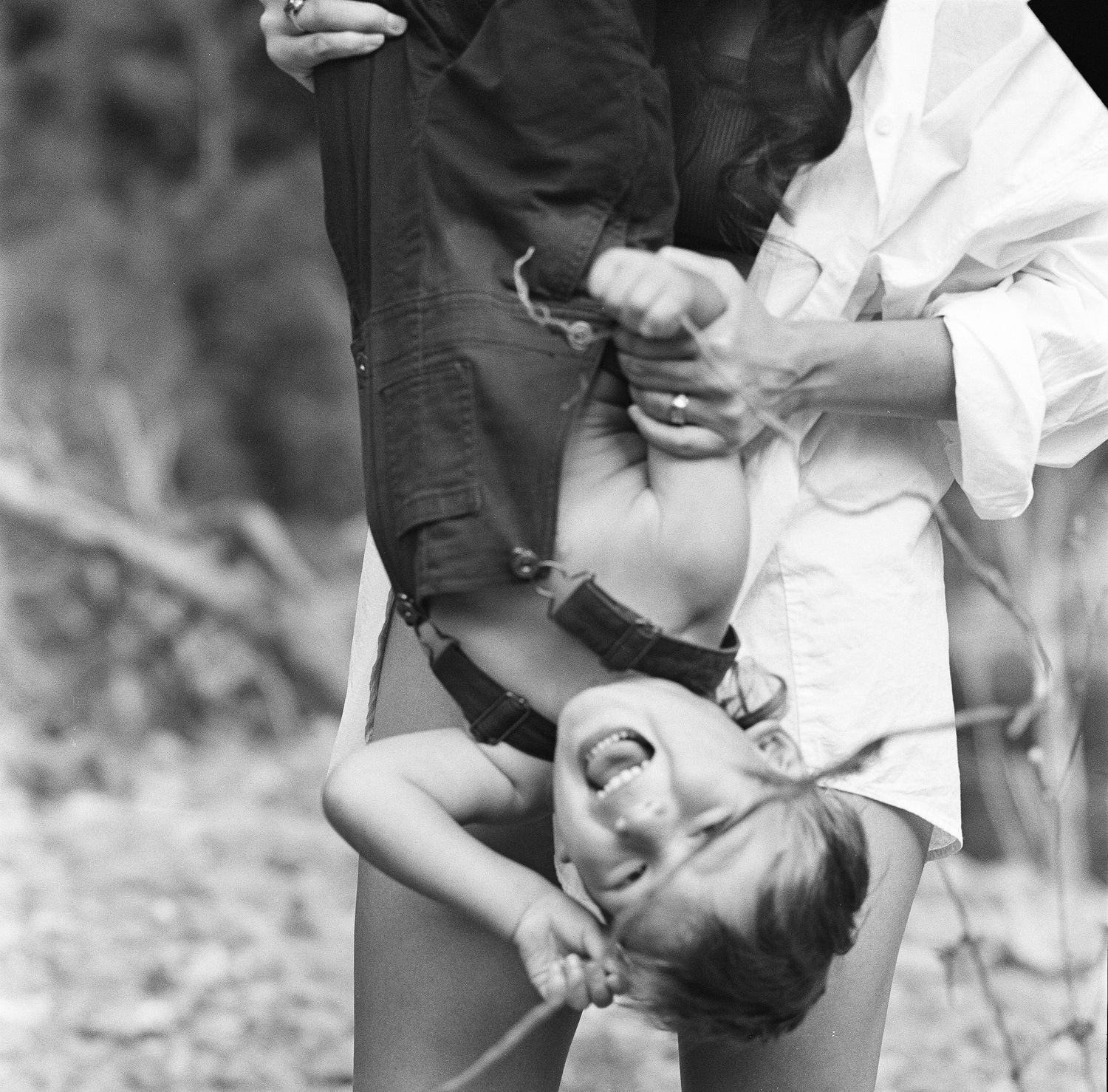 Vintage black and white photo of a child being playfully held upside down.