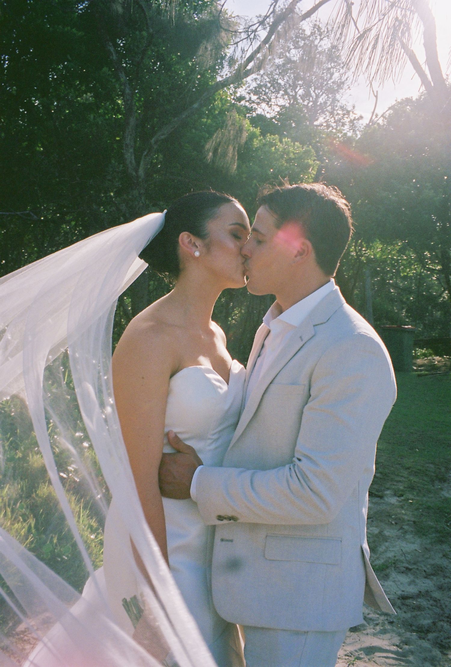 A romantic wedding moment captured in a sunlit garden setting.