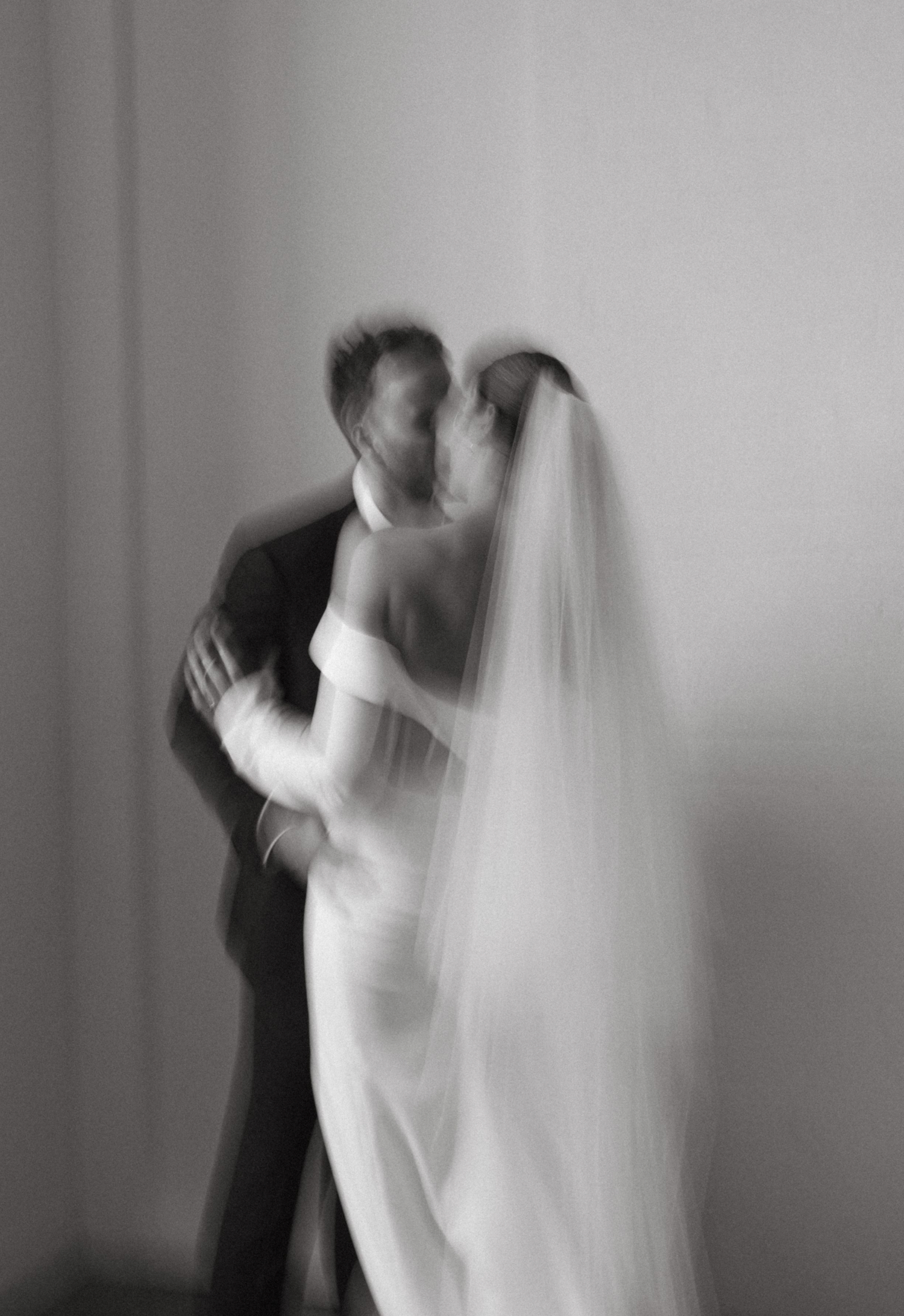 A romantic black and white wedding photo showing a bride and groom embracing in an intimate dance pose.