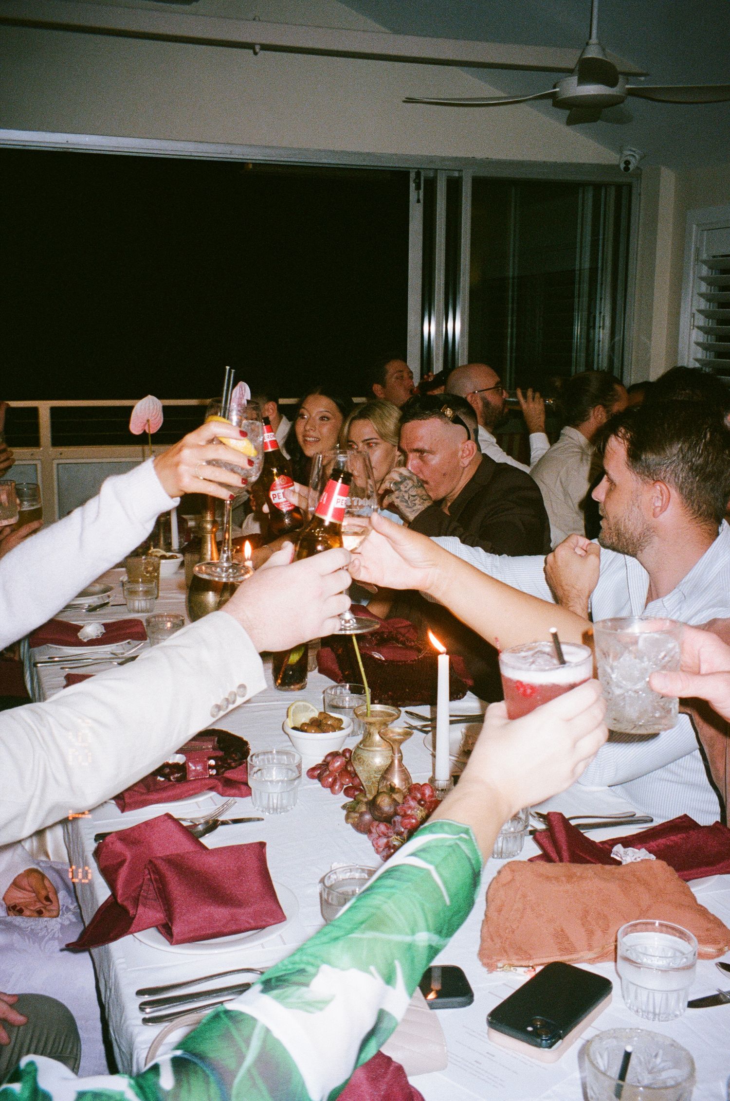 Guests at a formal dinner party raising their glasses in a toast across a long dining table.
