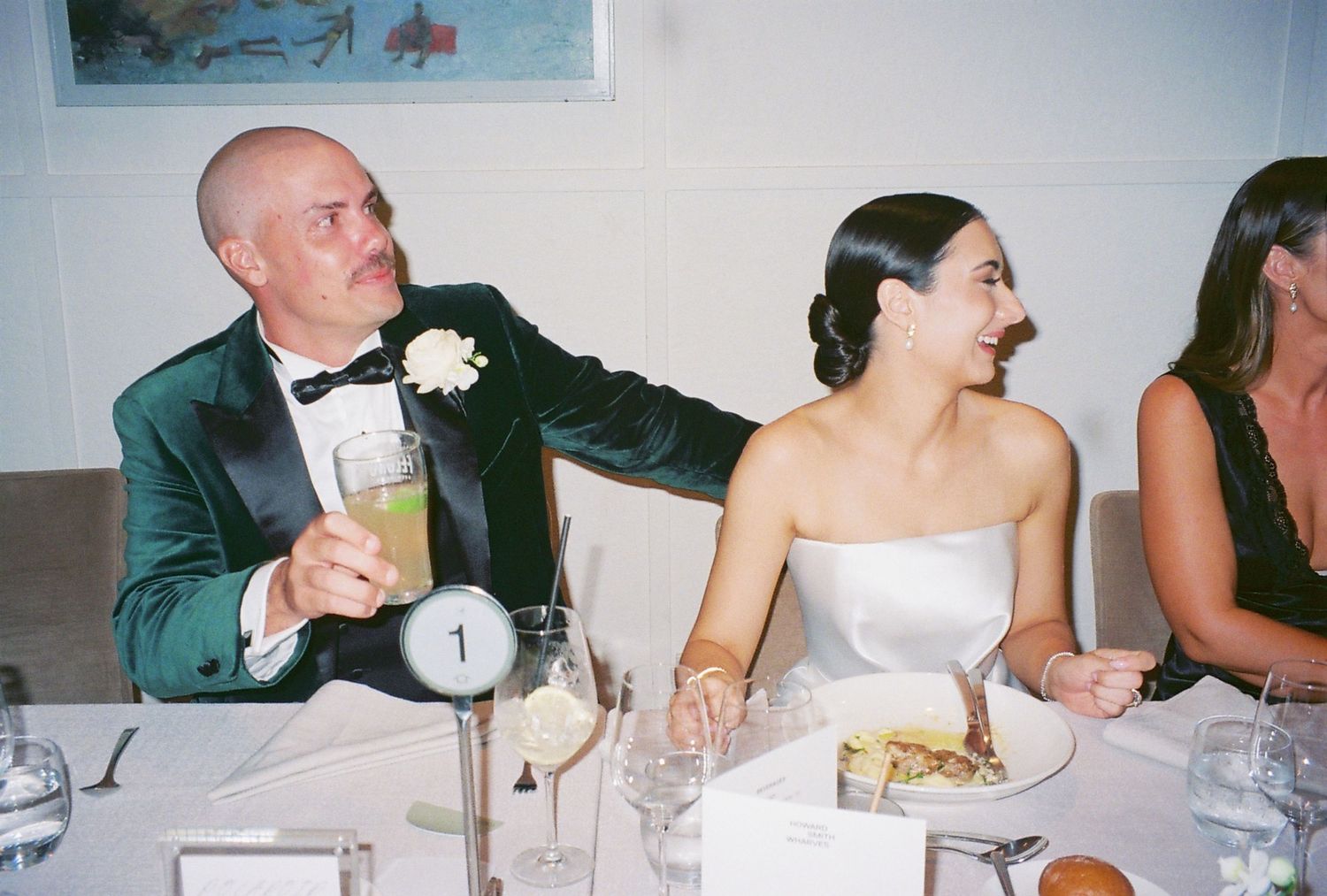 Reception guests seated at a formal dinner table enjoying conversation and laughter.