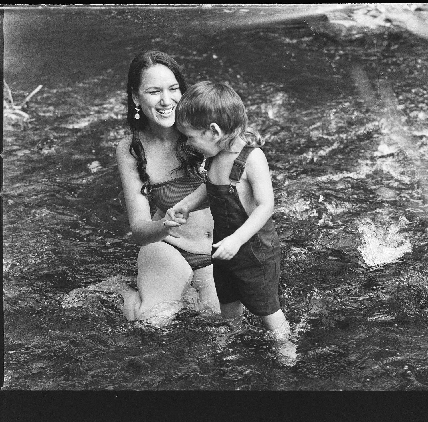 A joyful moment captured in black and white as parent and child play in the water.