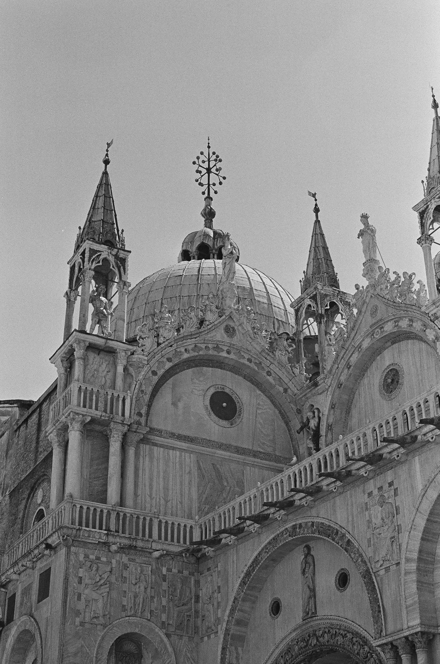 Ornate dome and spires of Saint Mark's Basilica in Venice against grey sky.