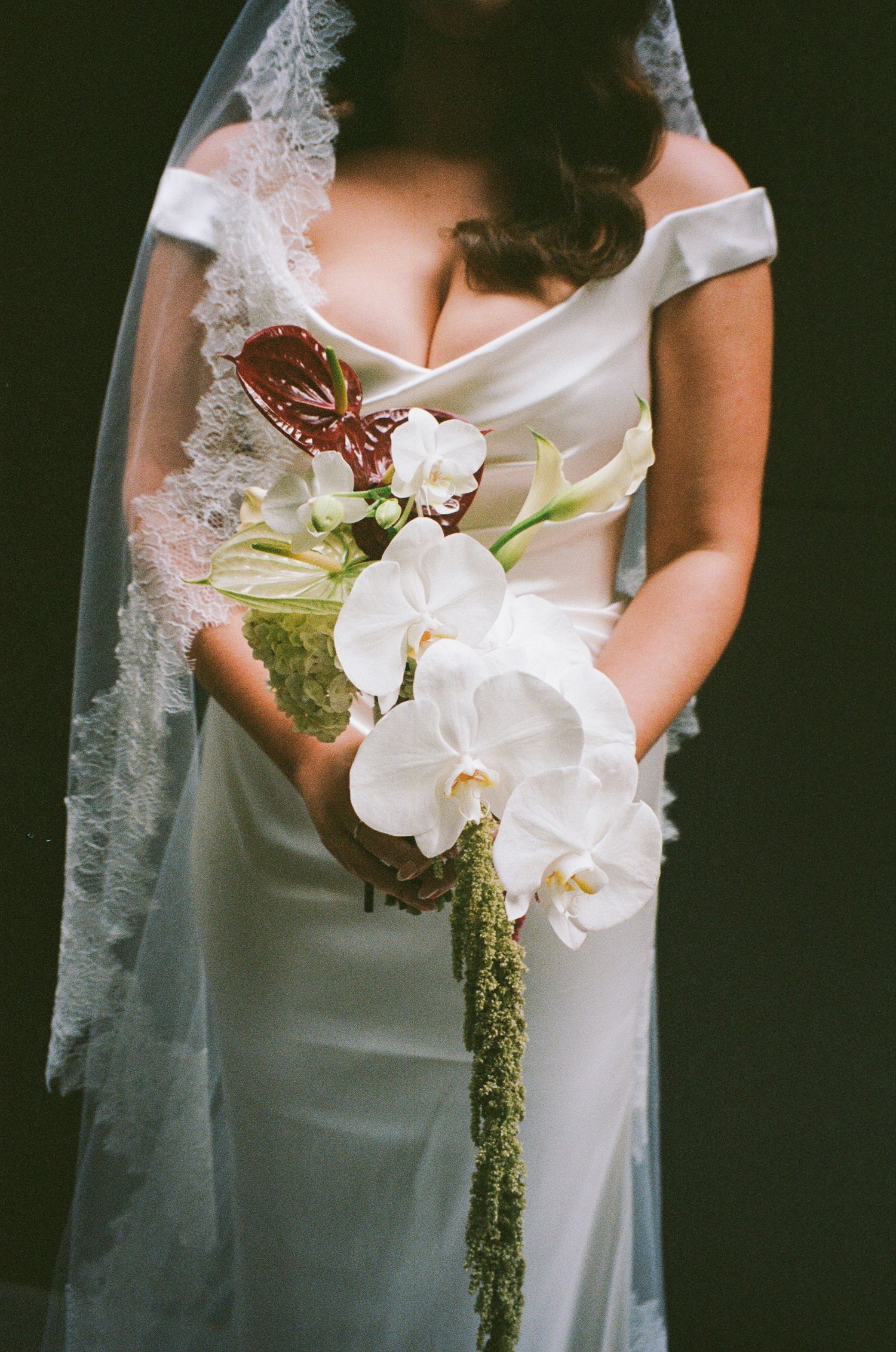A delicate white orchid and butterfly bridal bouquet held against an elegant white wedding dress.