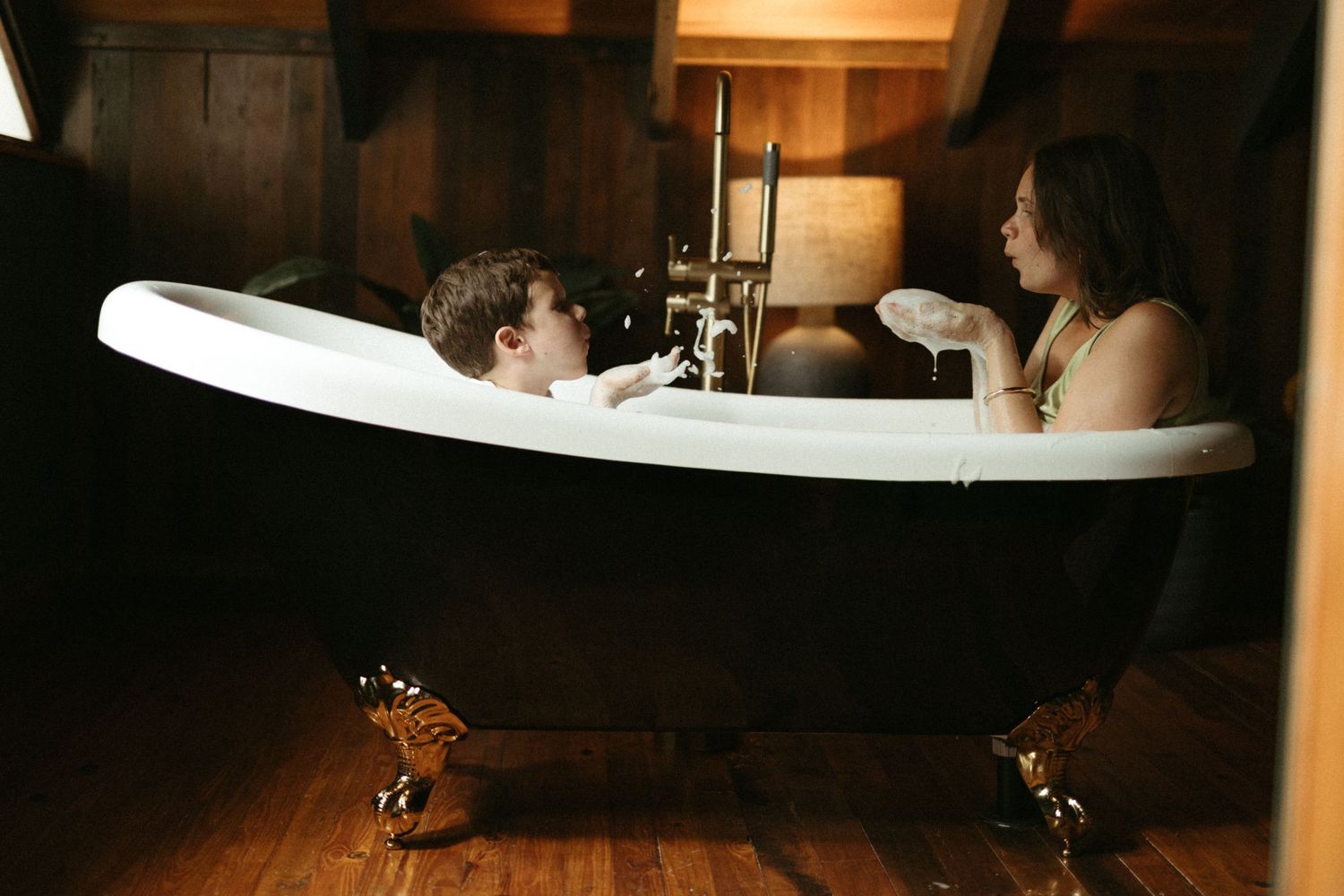 Two people sharing playful moment in vintage clawfoot bathtub.