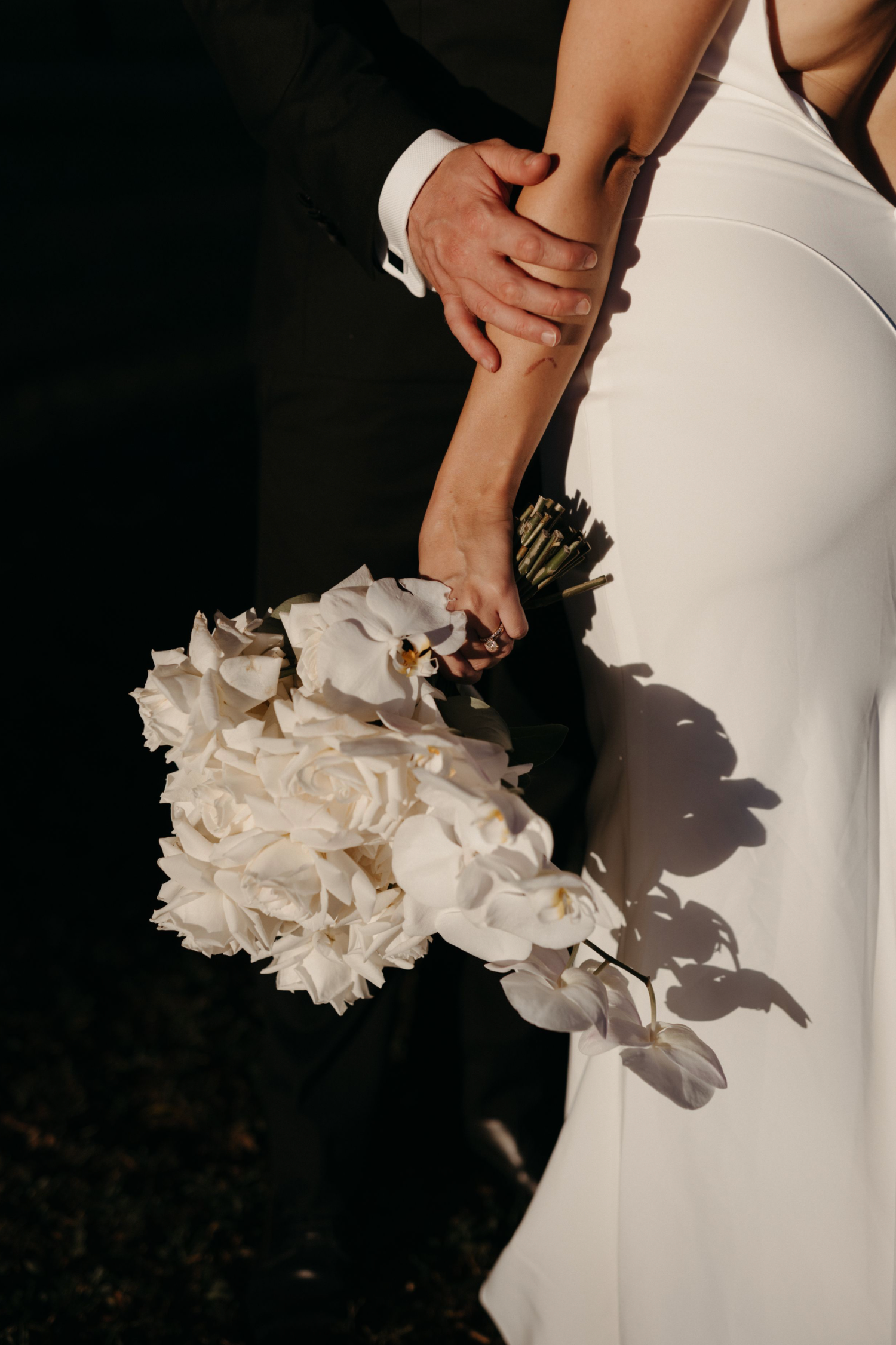 A close-up series showing a white ruffled wedding bouquet against an elegant white dress in dramatic lighting.