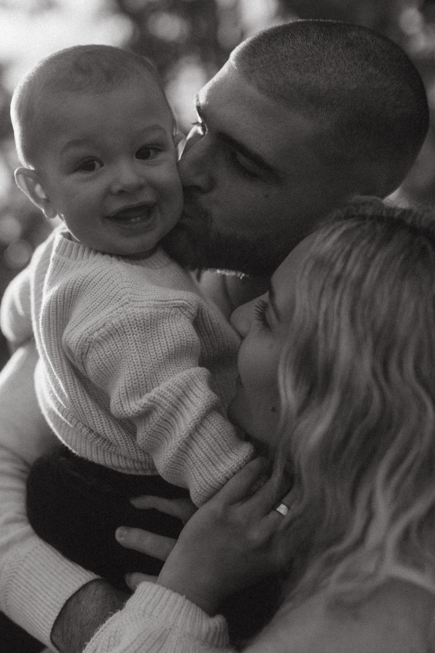 A heartwarming black and white photo series showing tender moments between a parent and baby in matching sweaters.