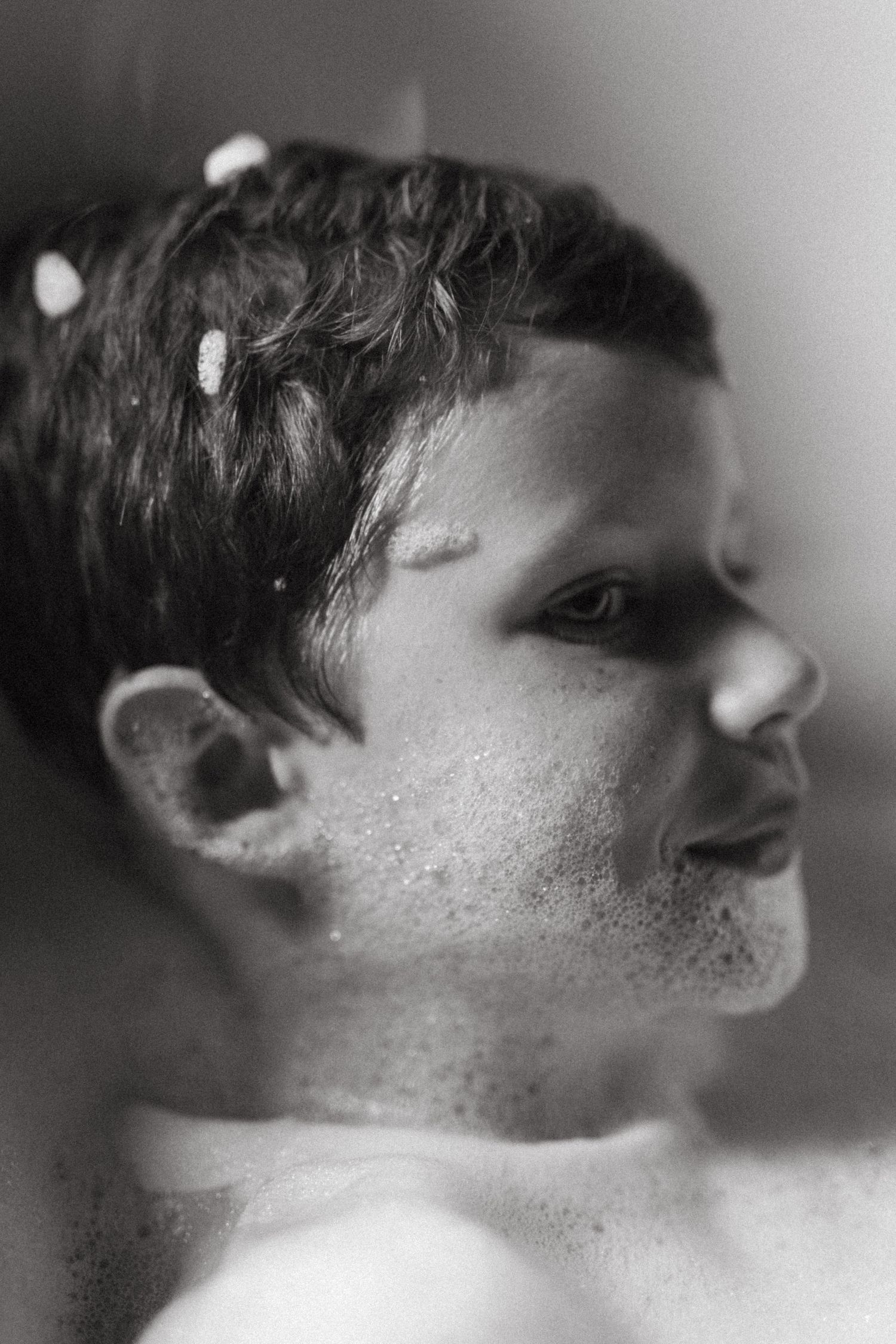 A dreamy black and white close-up portrait of a child with flowers in their hair.