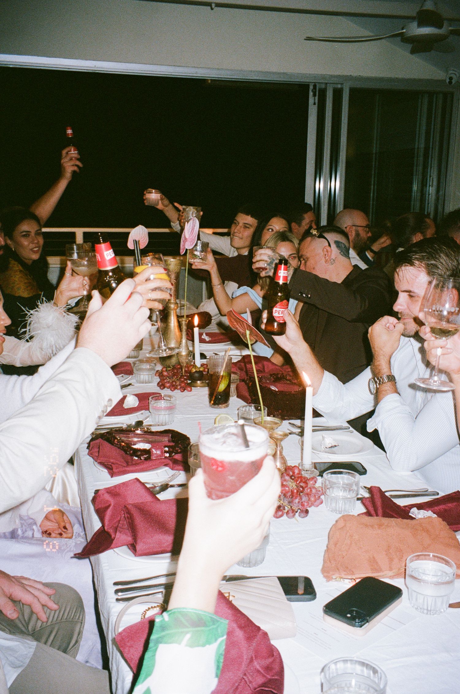 Group of people celebrating at a banquet with drinks raised in a toast at a long dining table setup.