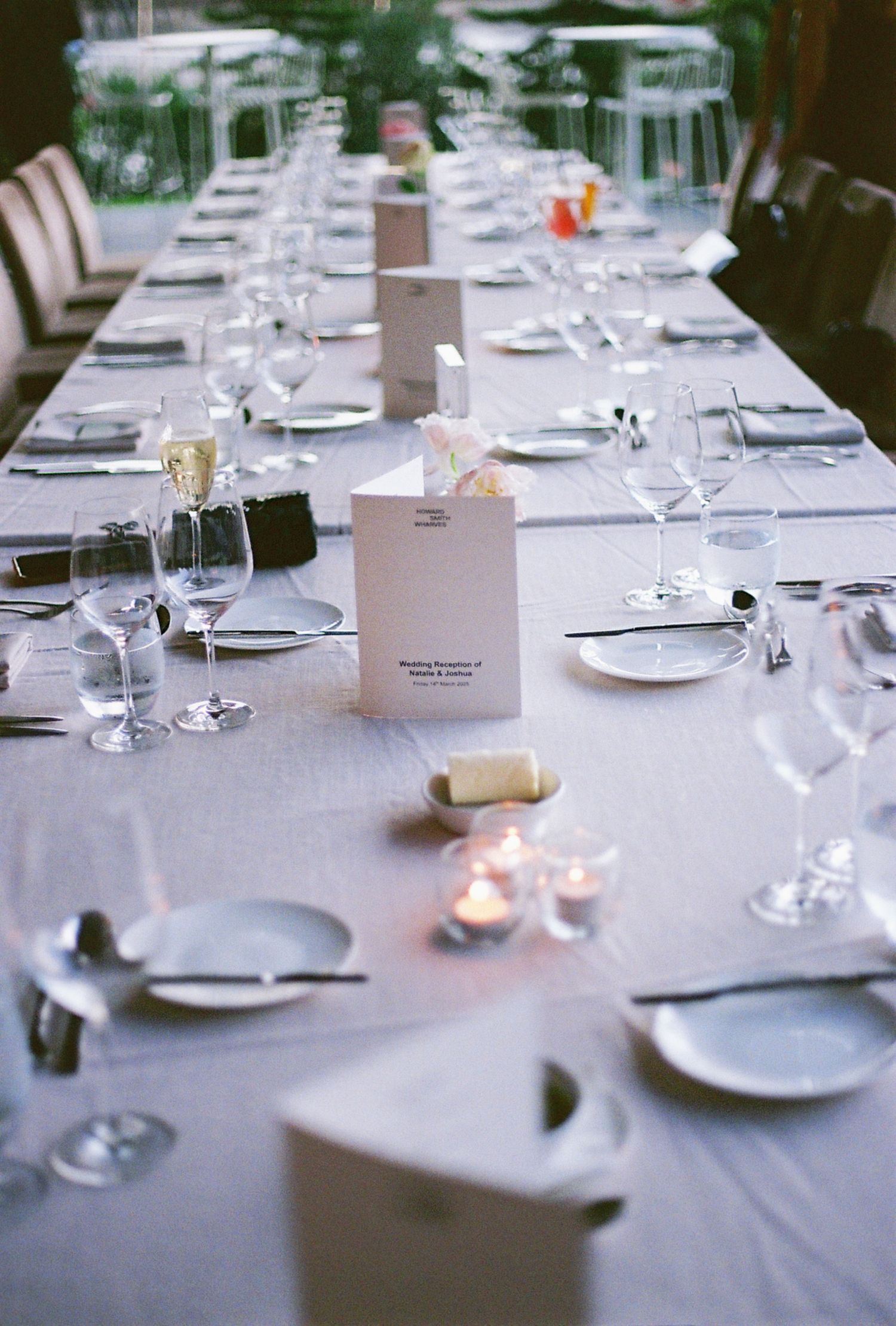 Elegant wedding reception table setting with white linens, wine glasses, and place settings.