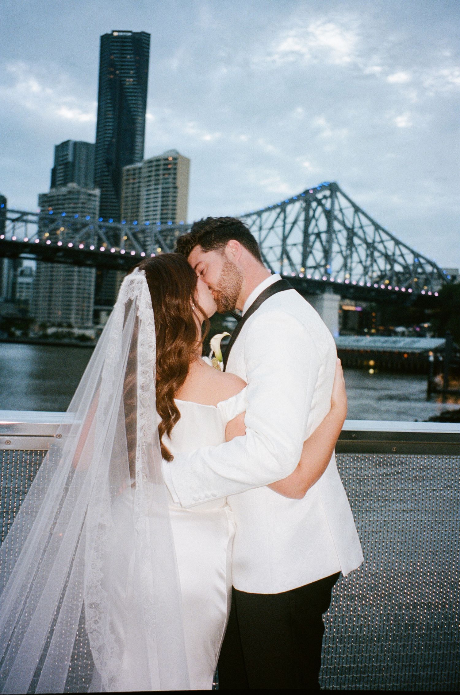 A romantic wedding photoshoot sequence showing newlyweds with a dramatic city bridge and skyscraper backdrop.