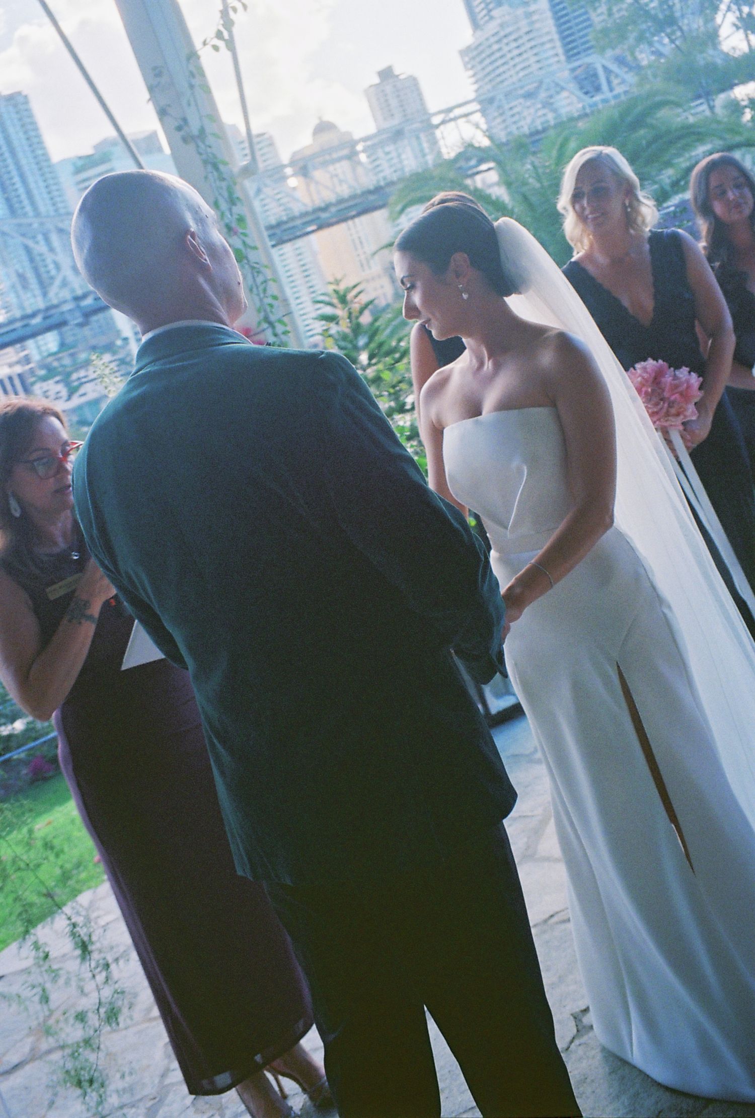 An outdoor wedding ceremony with city skyline and bridge in the background.