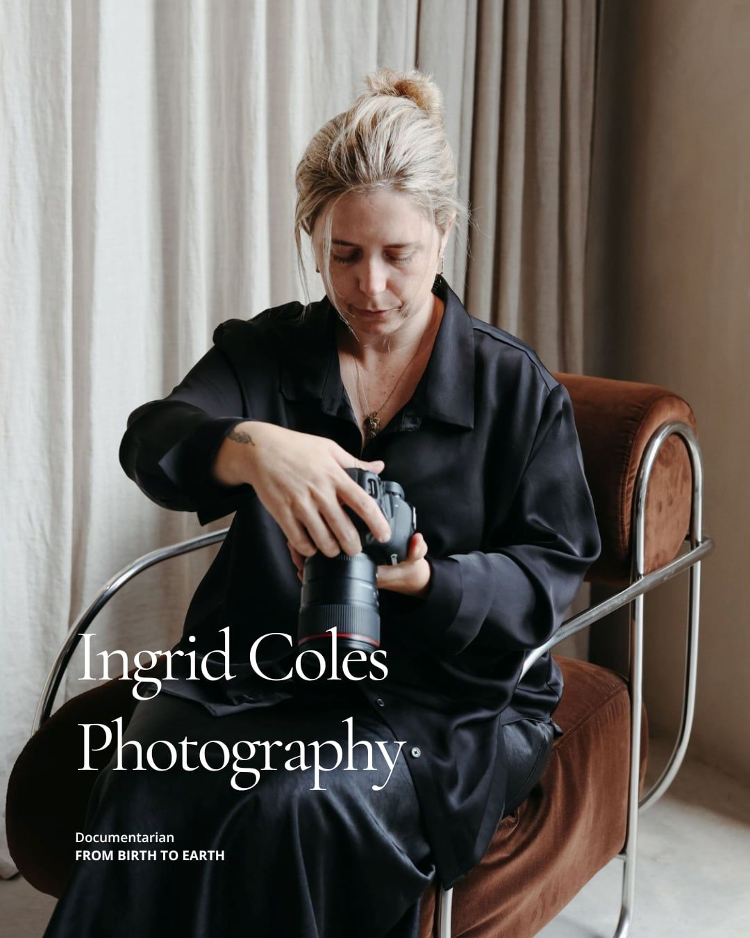 A woman in black attire sits in a wooden chair while working with photographic equipment in a bright interior space.