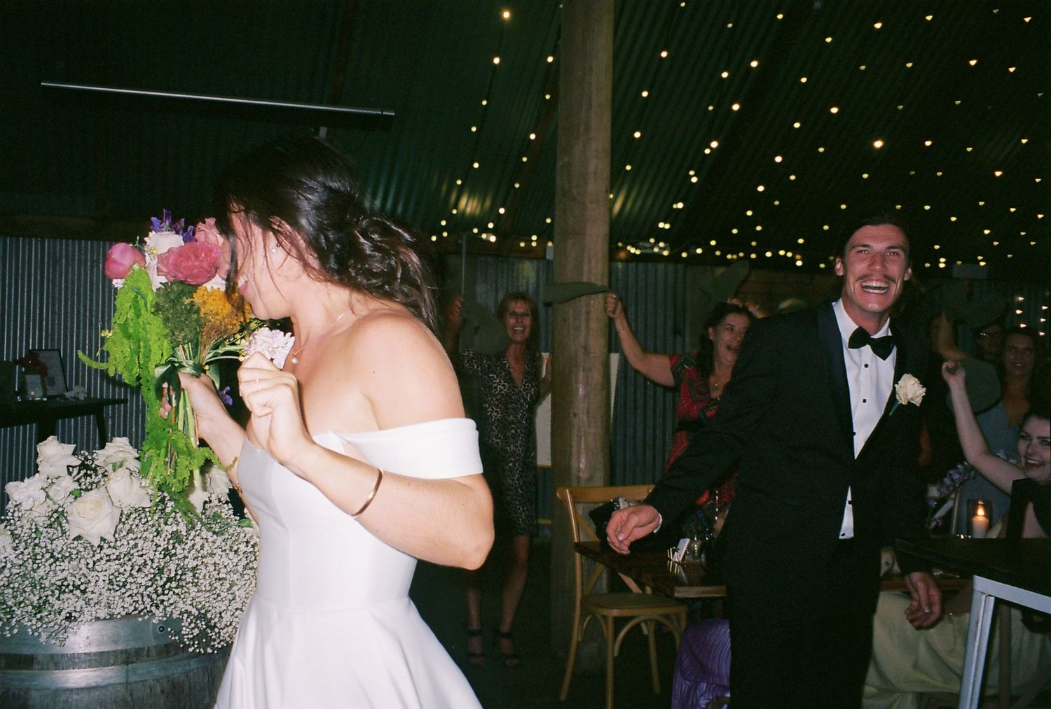 A joyful celebration moment at a wedding reception under string lights.