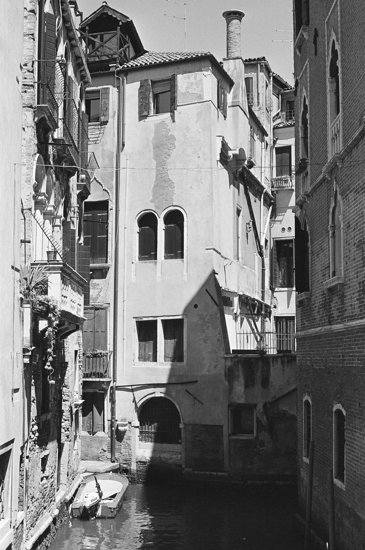 Narrow Venice canal between old buildings with arched windows and traditional architecture.