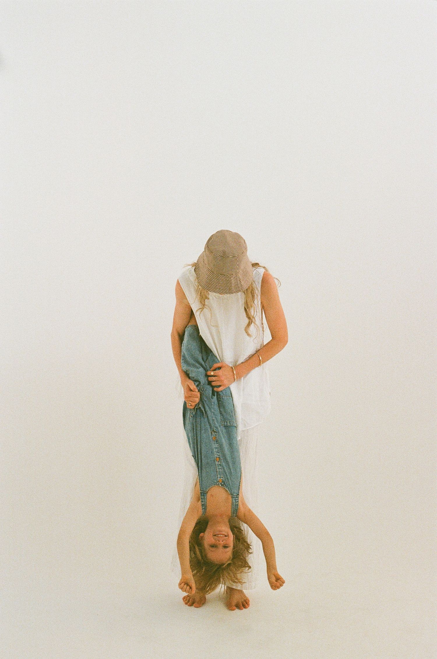Creative studio portrait showing someone being held upside down against white background.