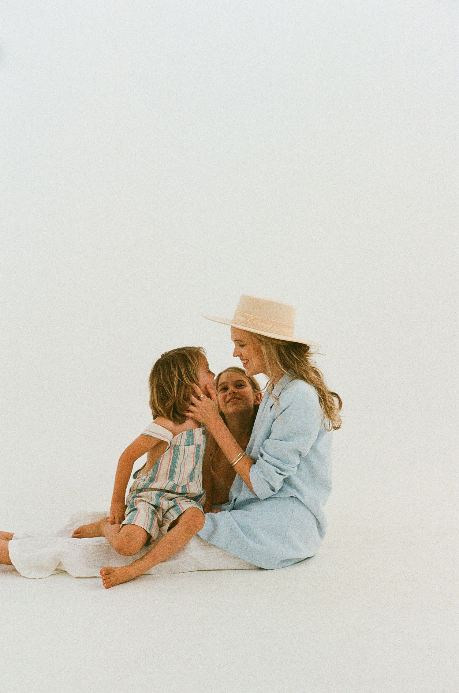 Intimate moment captured between two people sitting on white background wearing blue and white.