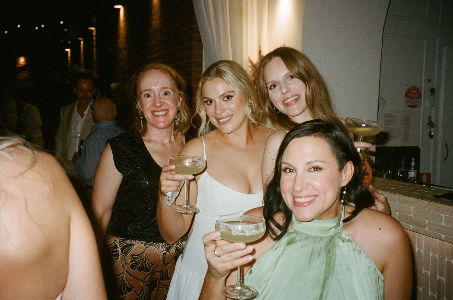 Wedding guests enjoying drinks and conversation at an evening celebration.