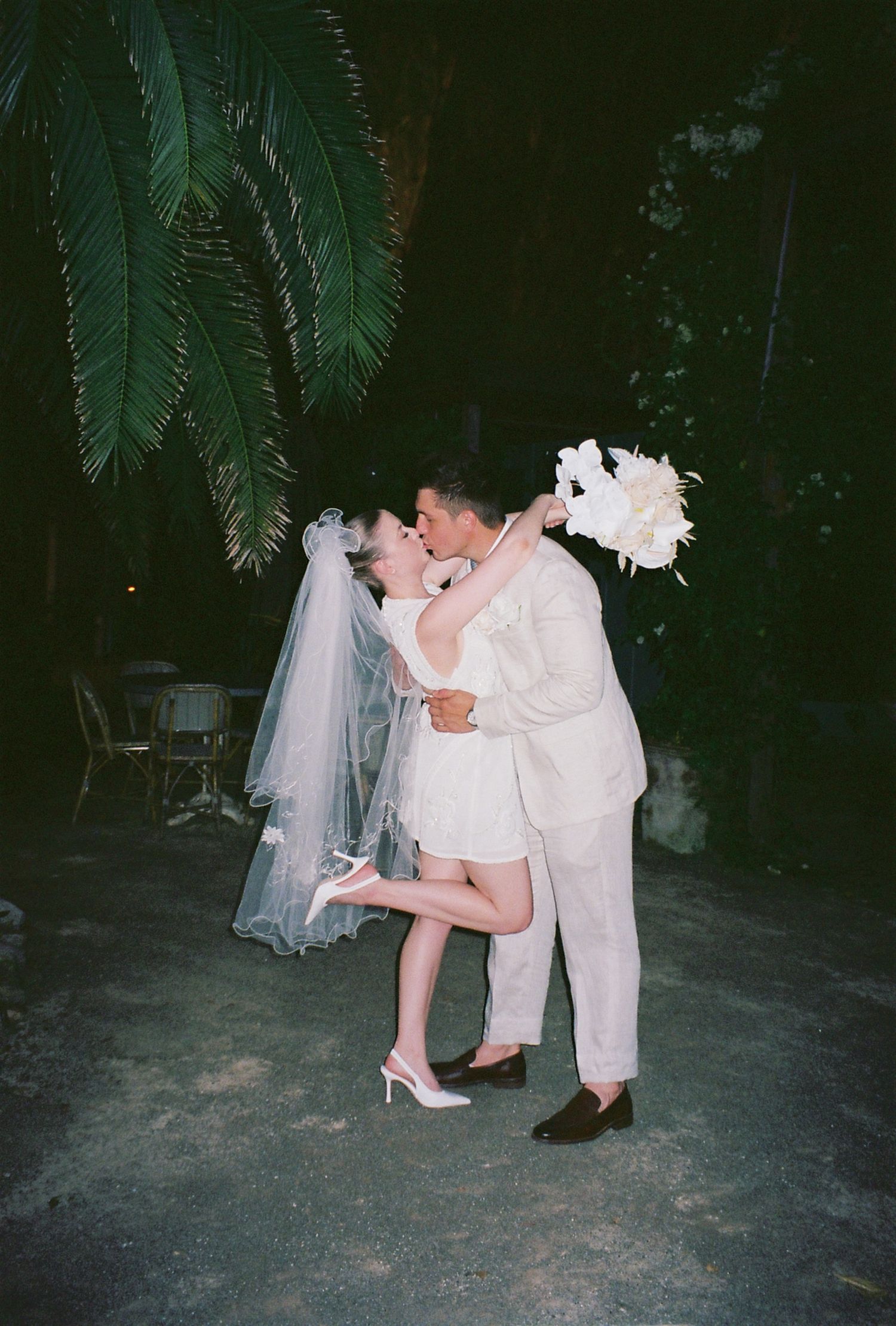 A romantic moment under palm trees at a tropical wedding venue.