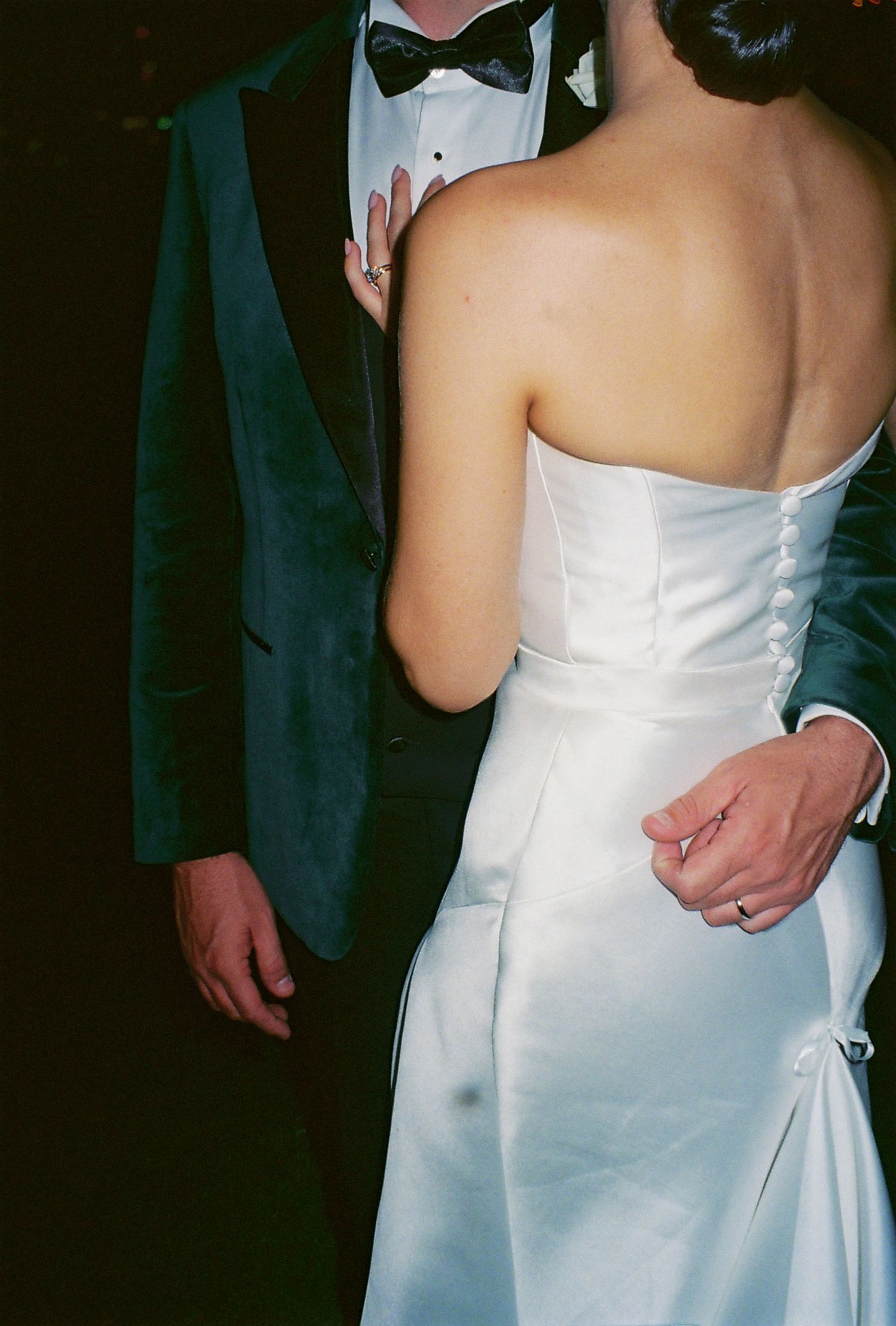 Close up of couple in formal attire, with bride in white strapless dress and groom in dark tuxedo with bowtie.