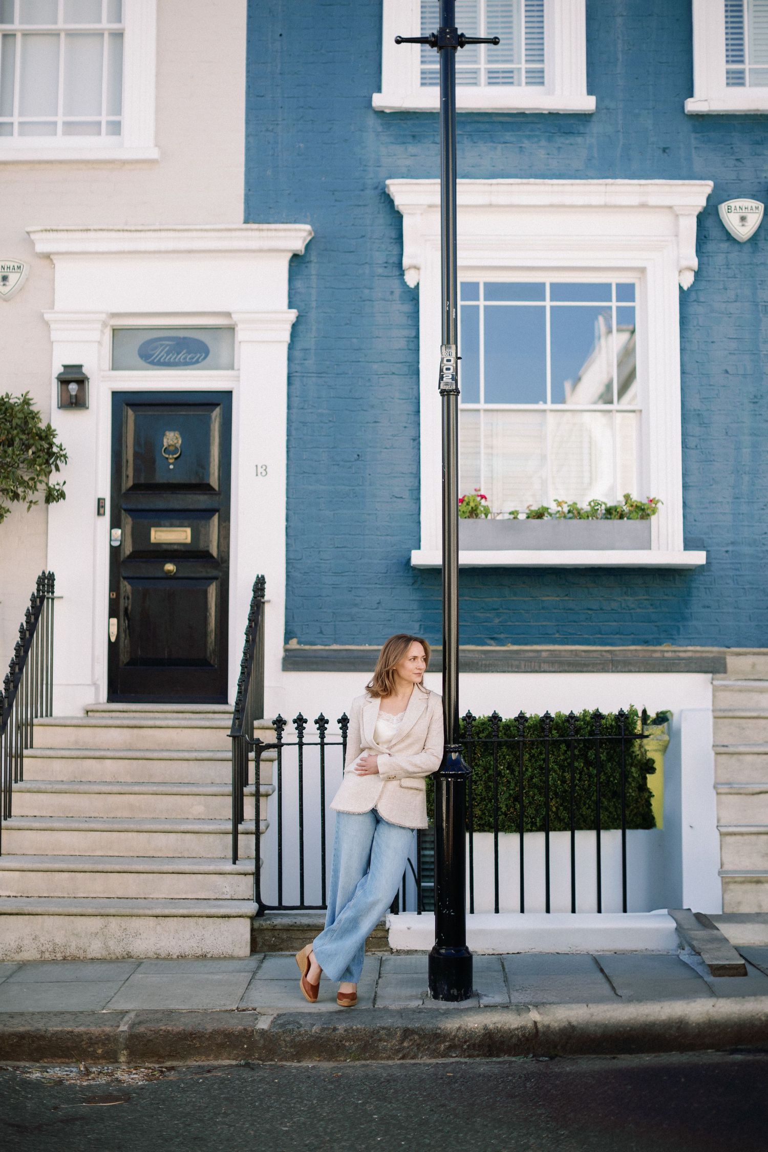 Miriam Caterina Wahl leaning against a lamp in Notting Hill with a blue house in the background