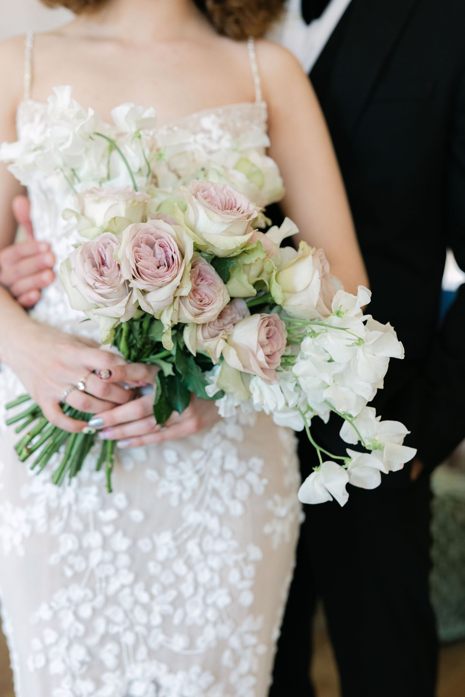 Soft pastel coloured flower bouquet with the bride and groom in the background