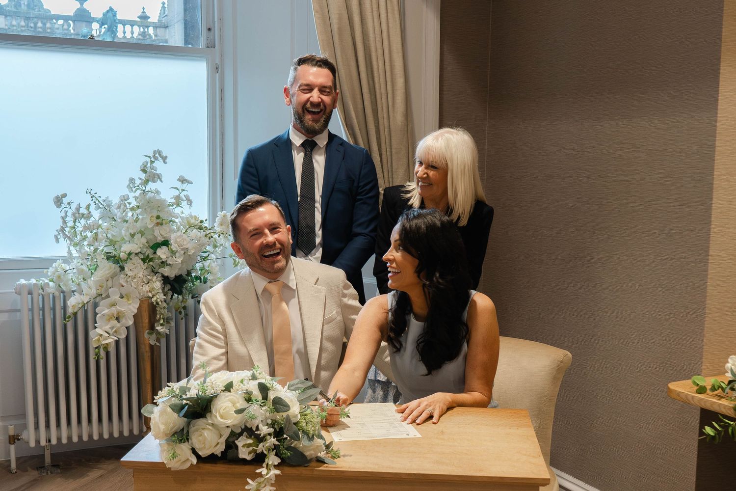 A small gathering in an elegant room with floral arrangements during an intimate ceremony.