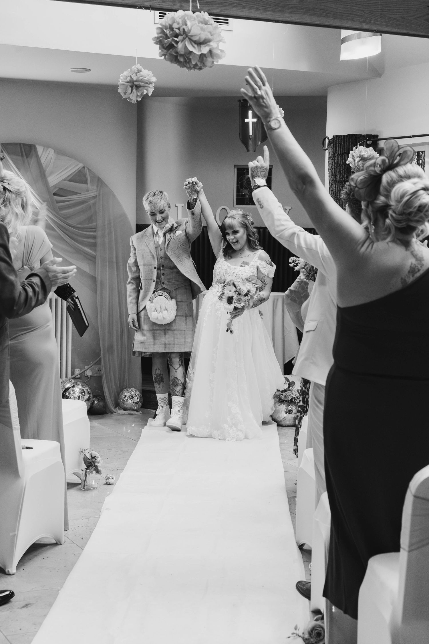 Black and white photo of wedding guests dancing and celebrating at a reception.