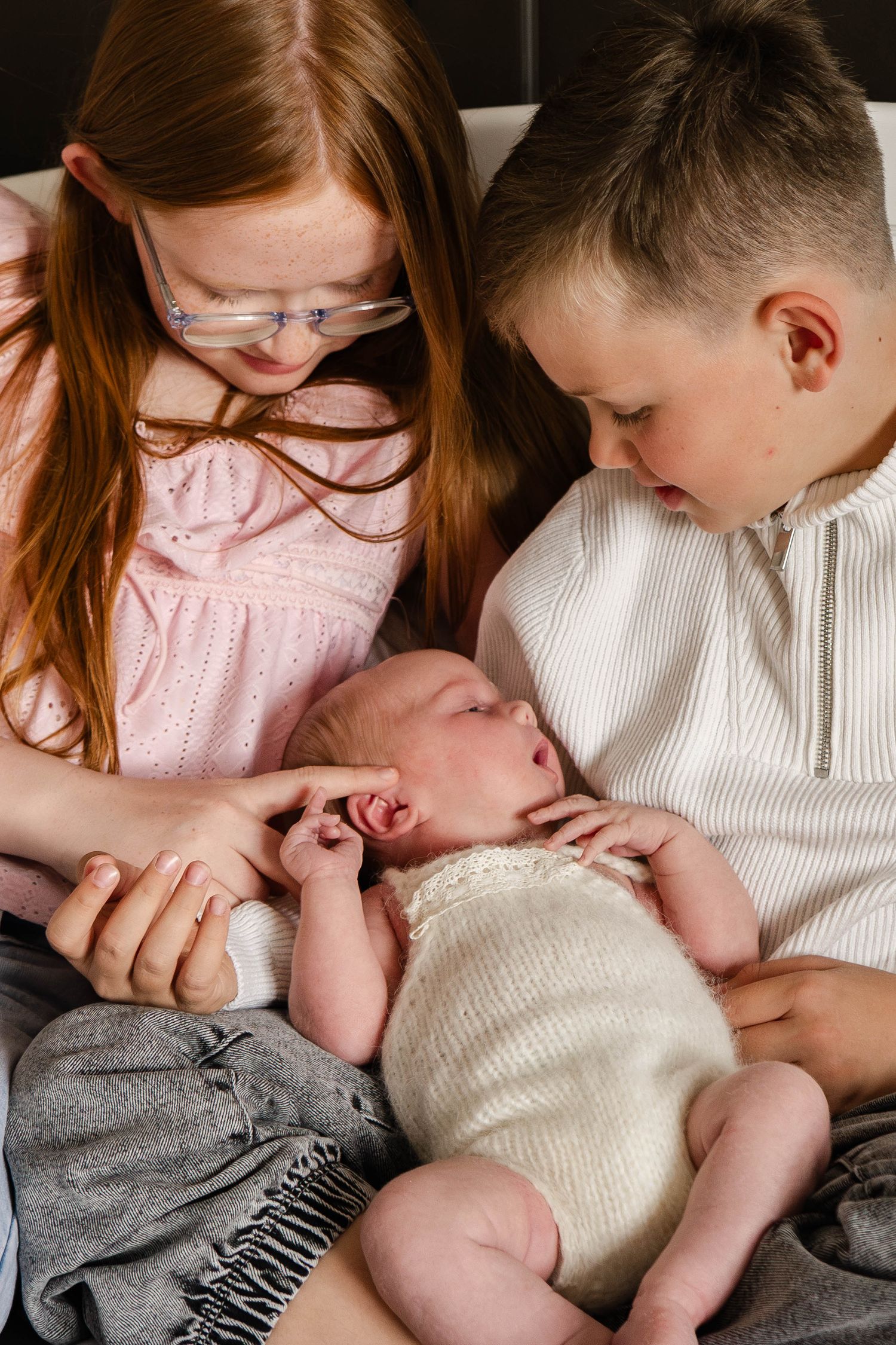 Sweet newborn photo session showing gentle family bonding moments on white bedding.
