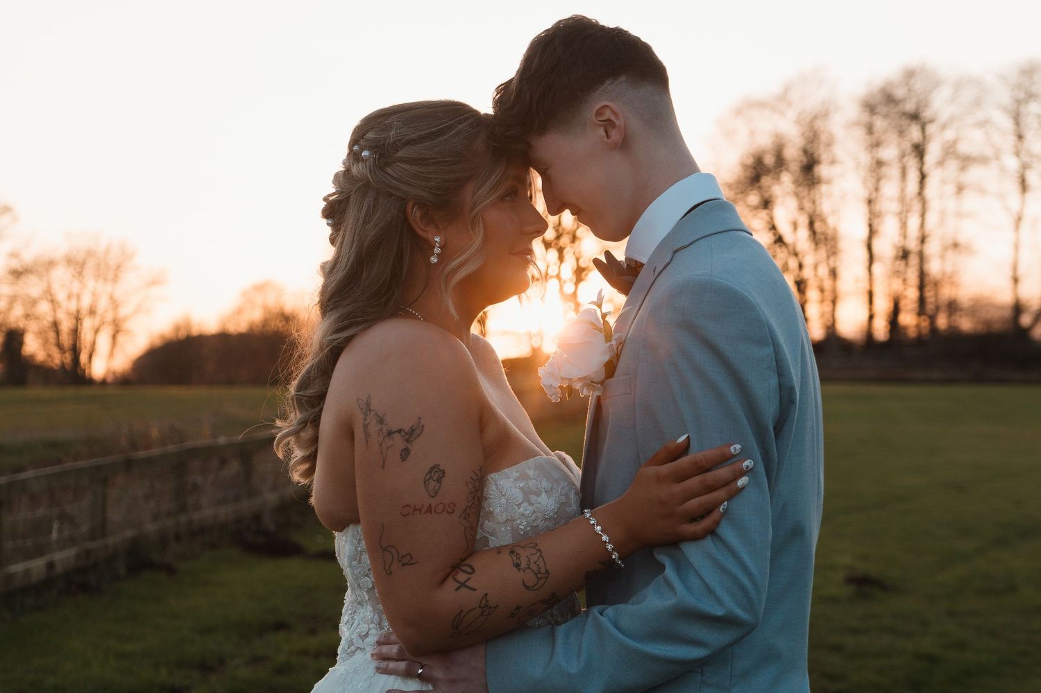 Bride and groom share a romantic sunset moment outdoors, with golden light glowing behind them on their wedding day.