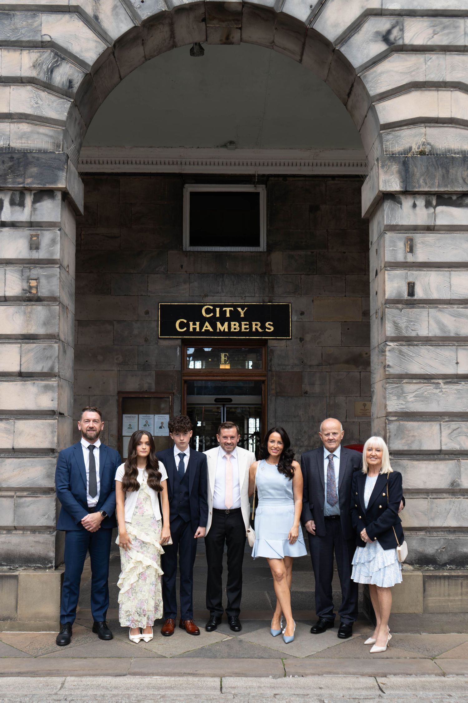 Wedding party group photo in front of City Chambers stone archway entrance.