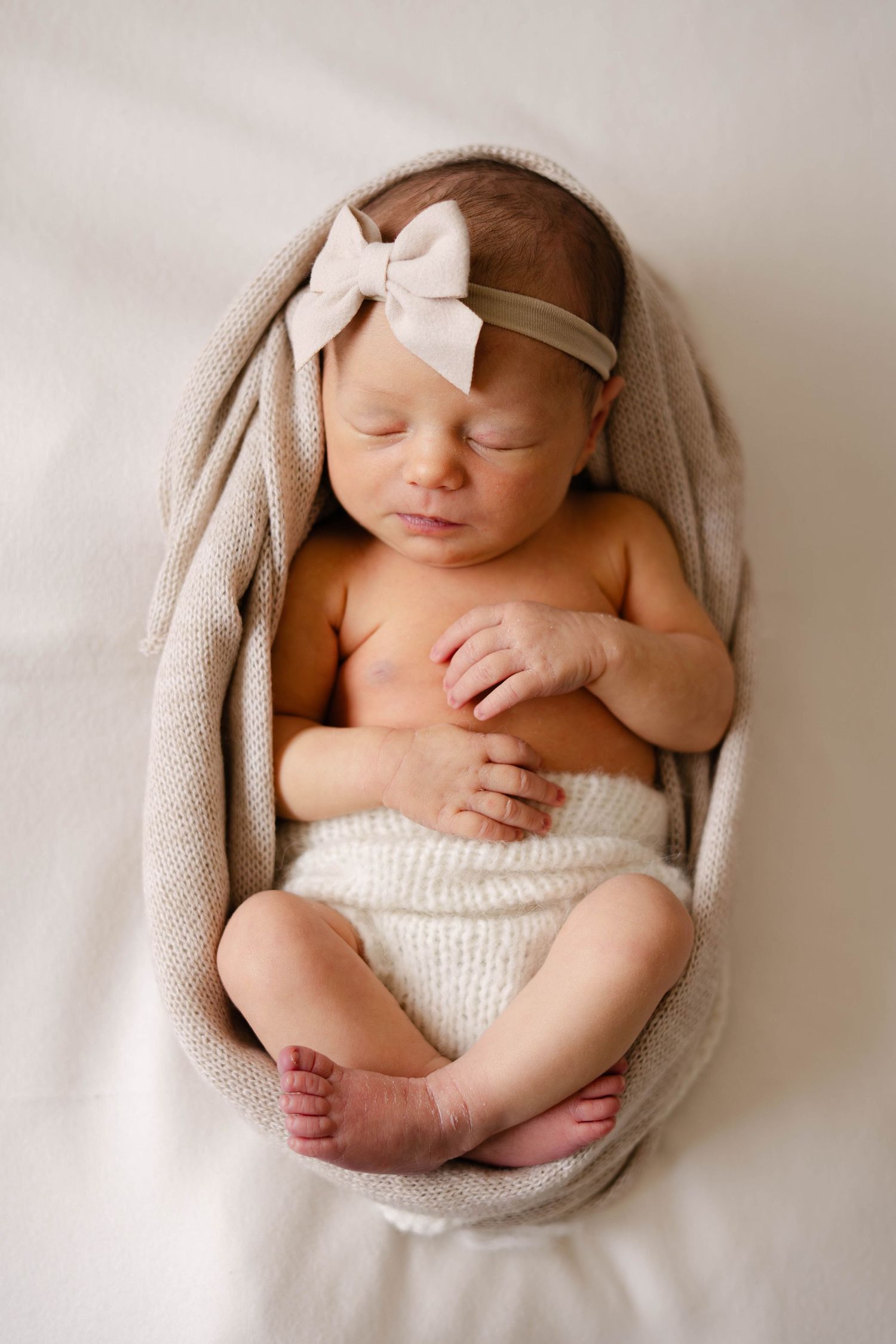 Artistic newborn photography series with baby in white knit wrap.