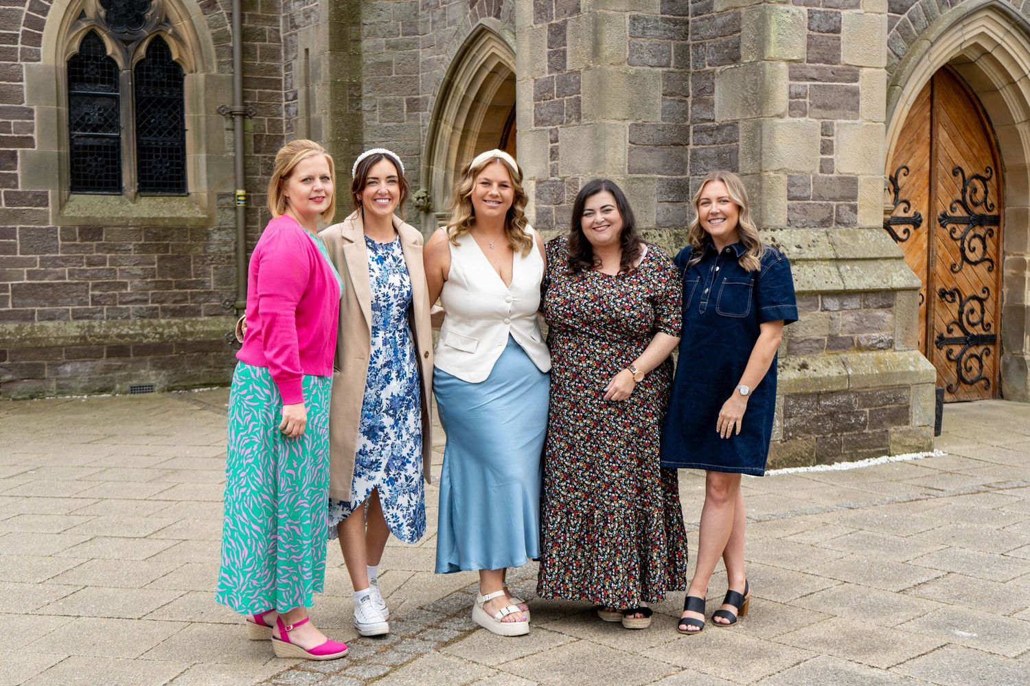 People gathered for formal photos outside a gothic stone church.