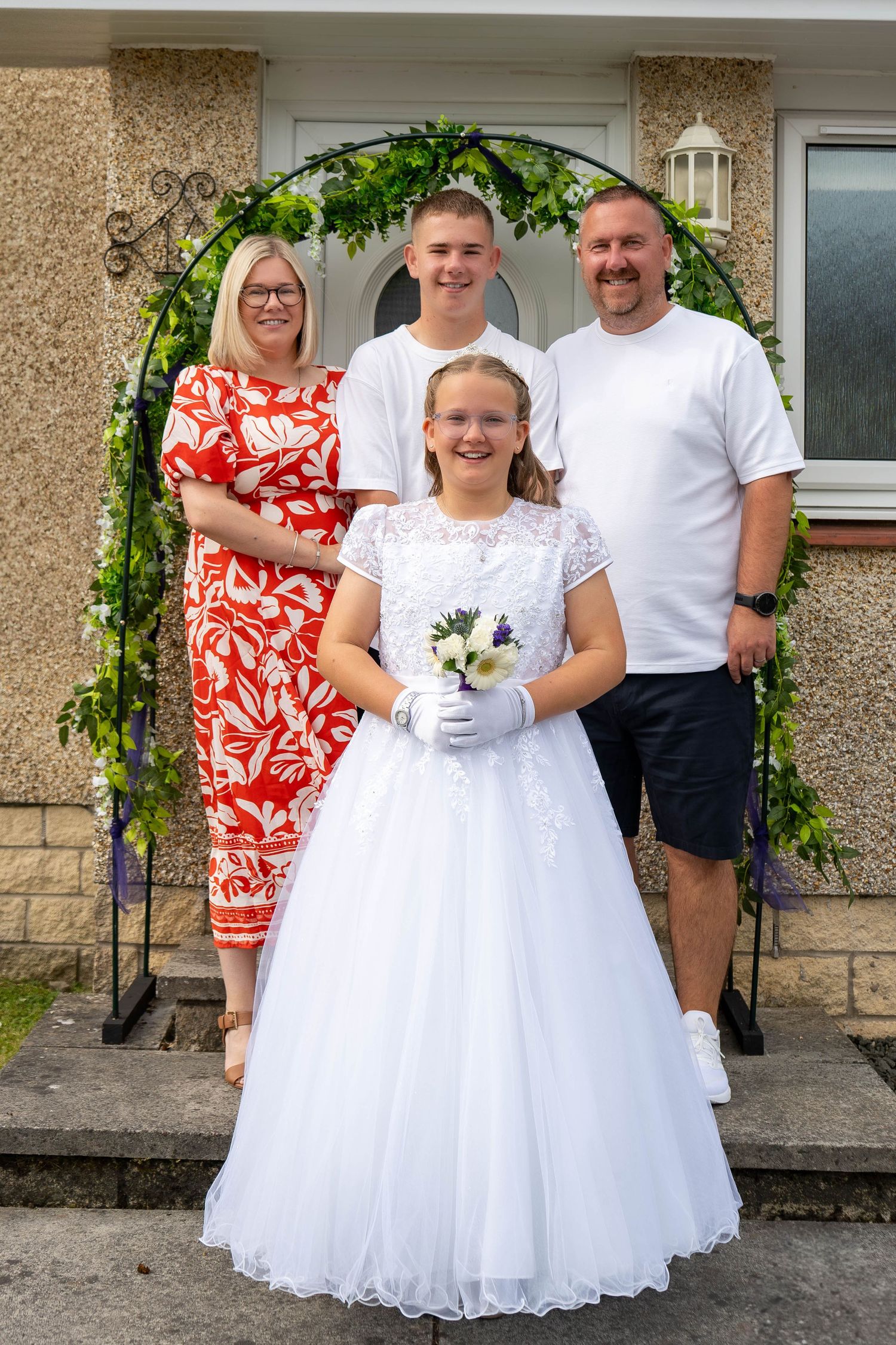 Family photos outside a house with children wearing white formal dresses.