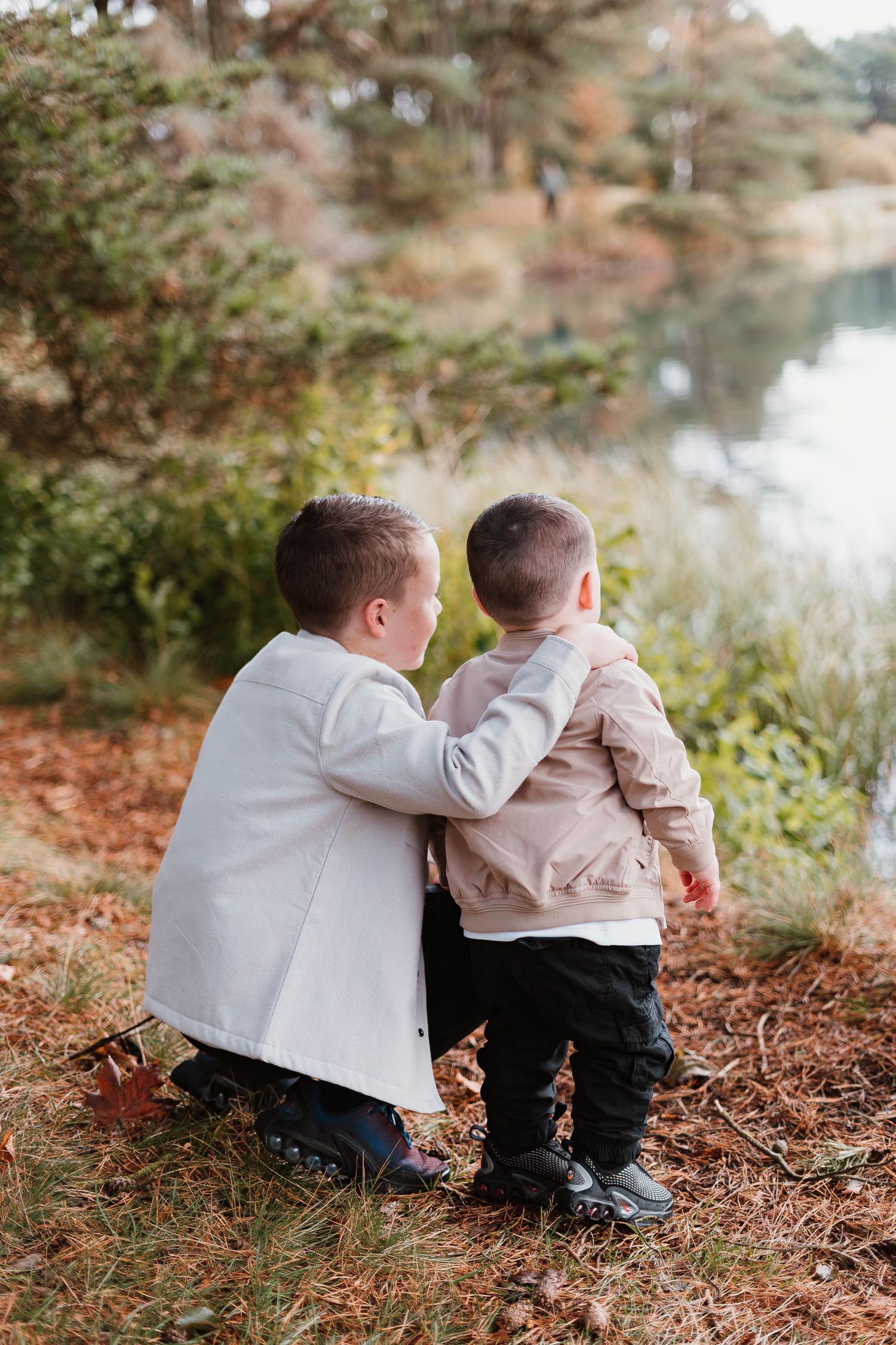 Series of outdoor autumn photos showing two children sitting by a lake.