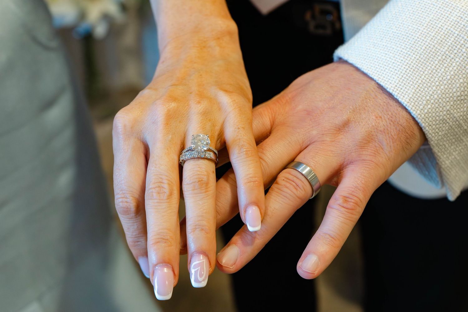 Close-up of hands displaying wedding rings with fresh manicure.