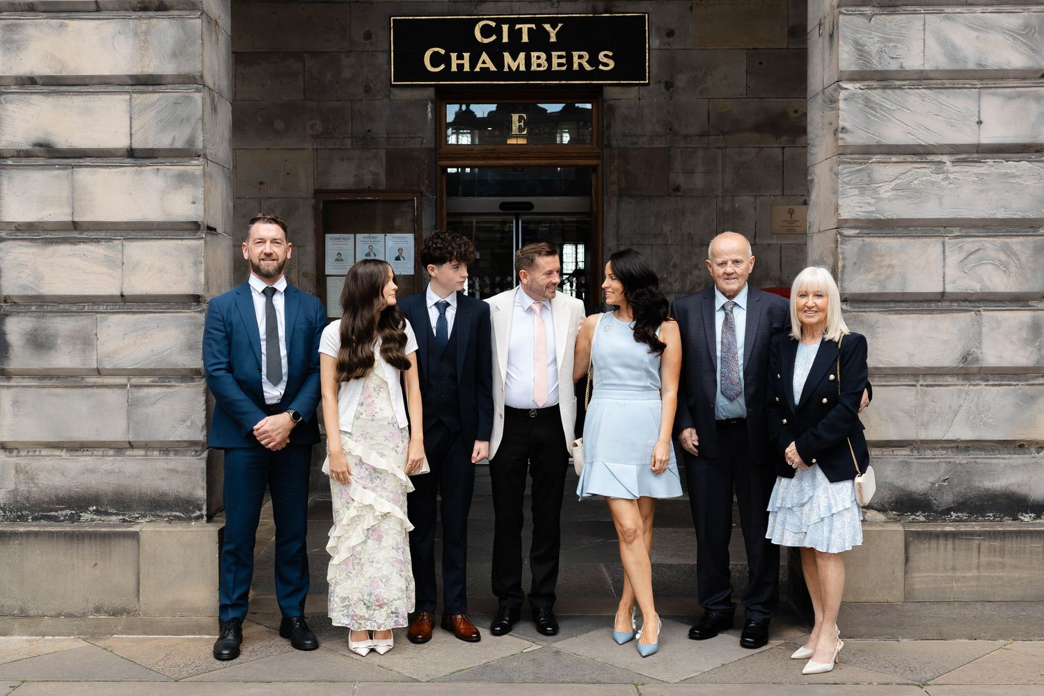 Formal group portrait of wedding party outside City Chambers building.