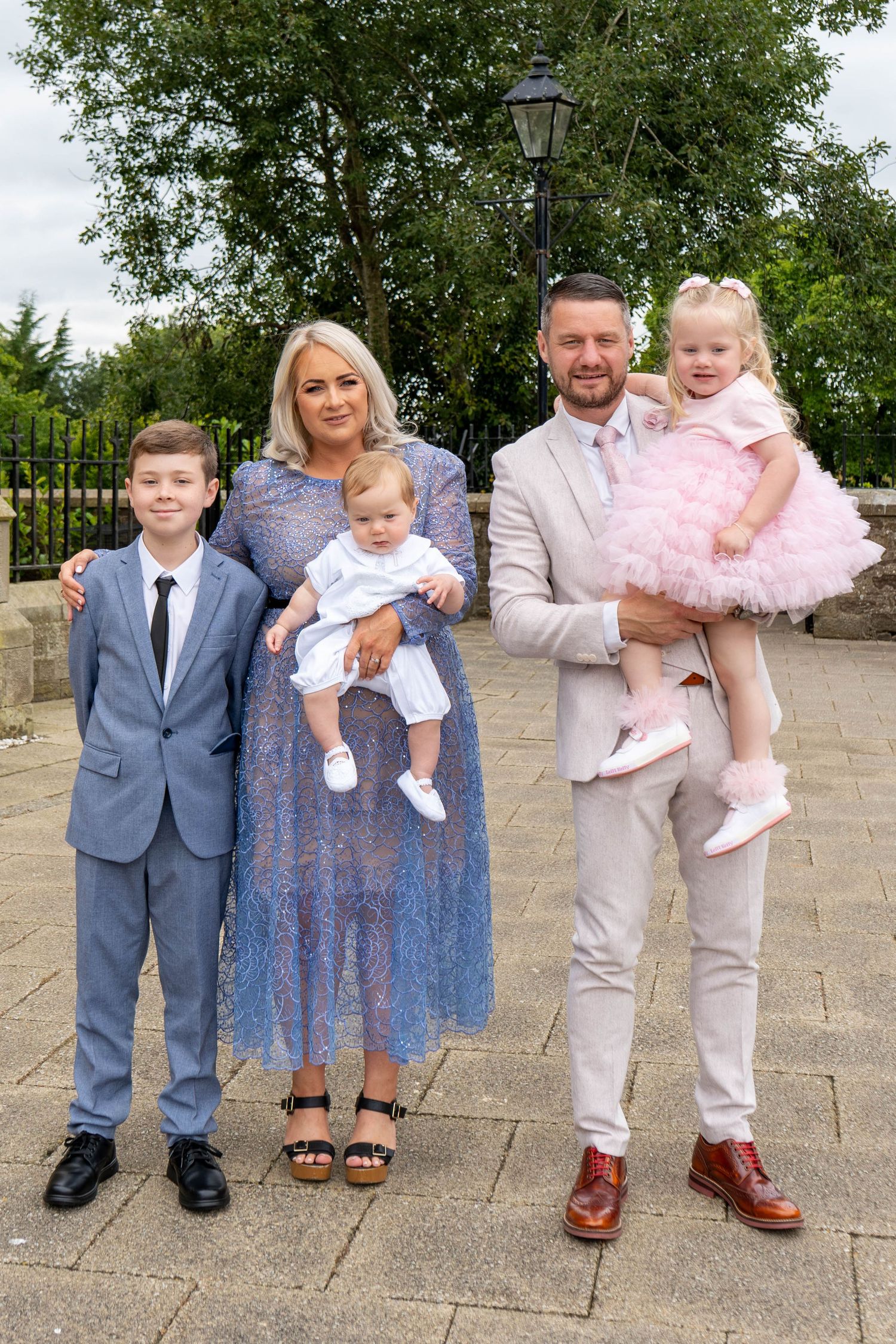Family group photos outside with children wearing formal attire and pink tulle dress.